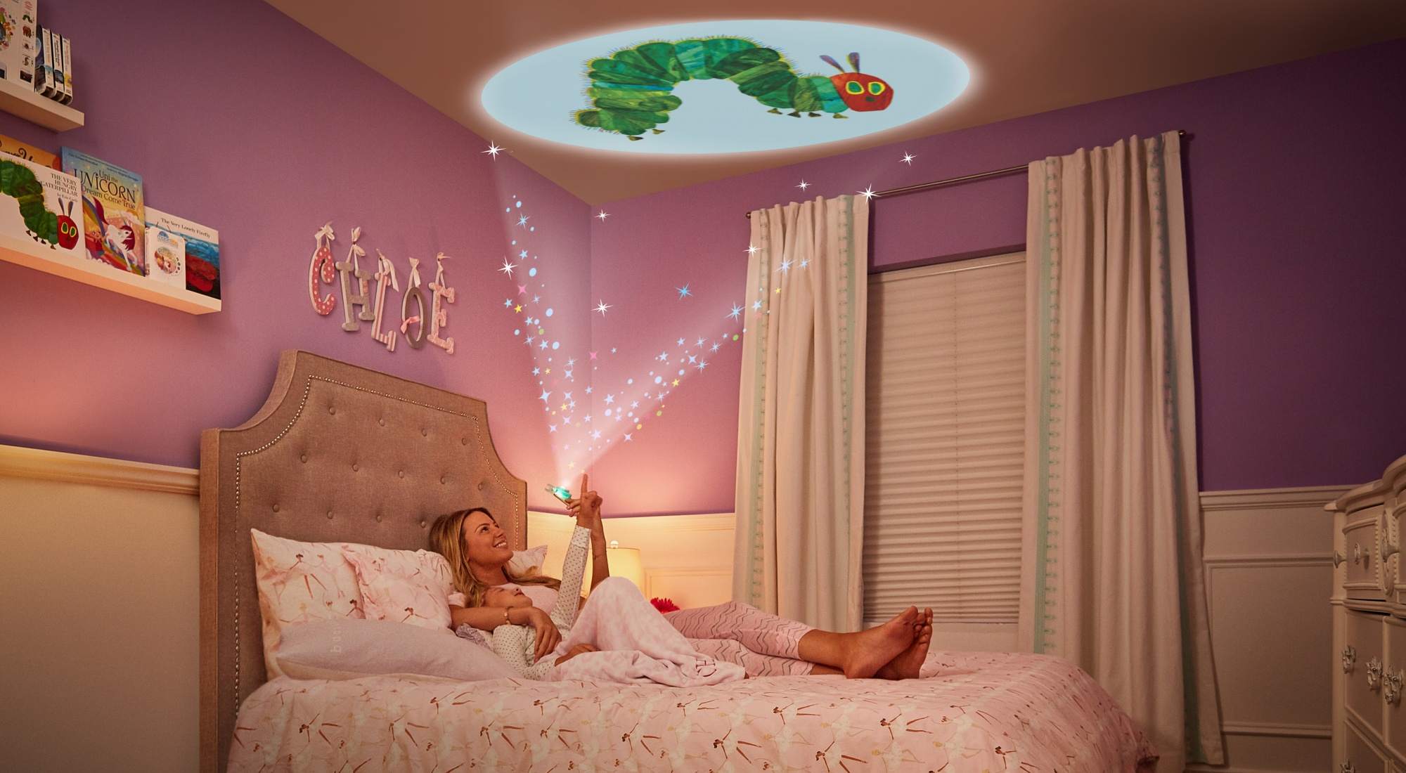 Kobieta i dziecko leżą na łóżku, patrząc na rzutowaną gąsienicę na suficie. Widoczne są gwiazdy.