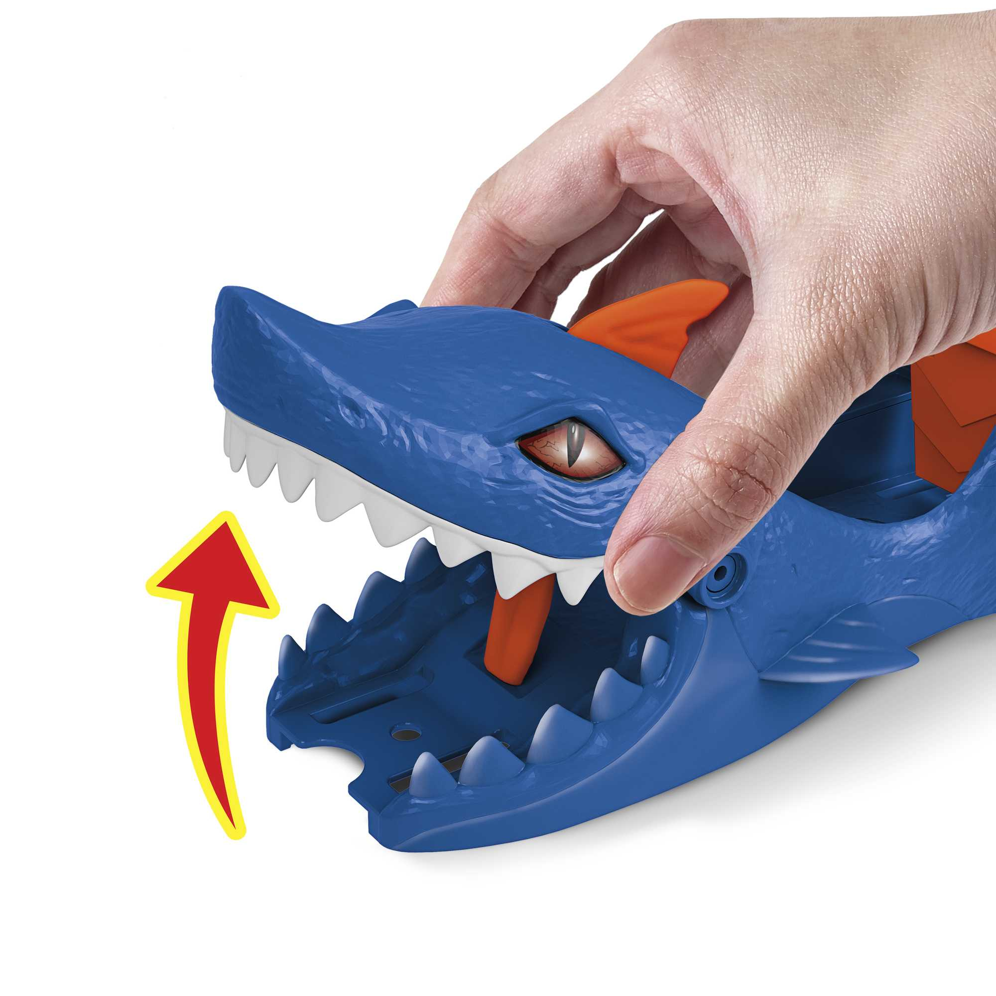 Ręka otwierająca niebieską zabawkę w kształcie pyska rekina ze strzałką.
