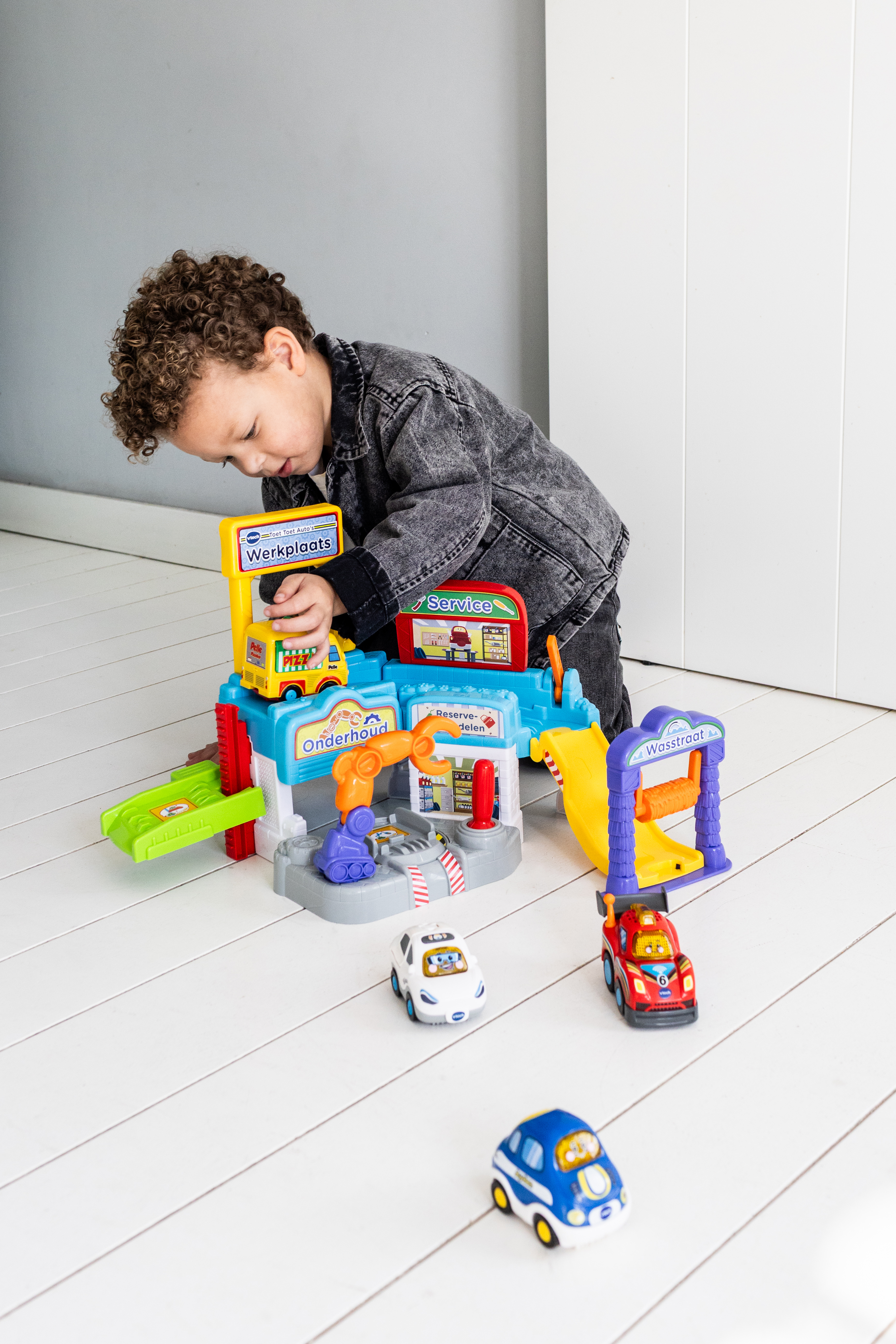 Un niño jugando con un juego de garaje VTech, con coches y una estación de servicio.