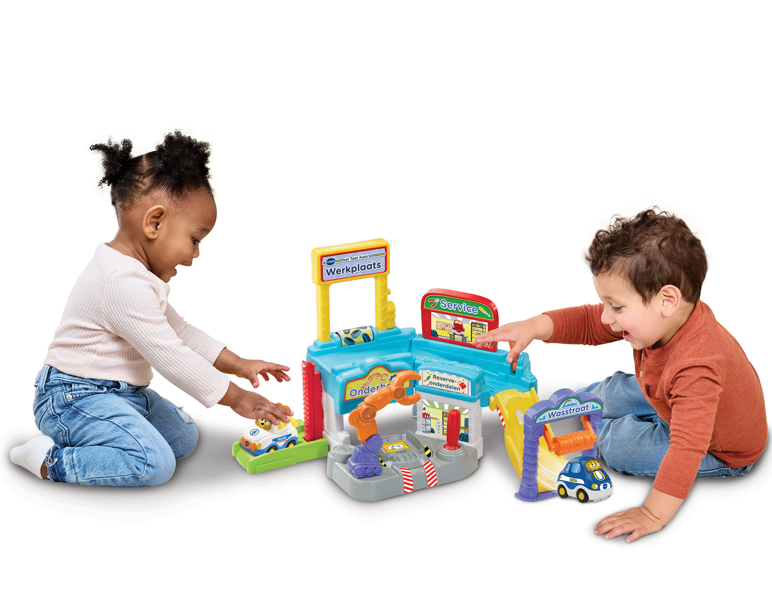 Dos niños juegan con un juego de garaje VTech, coches y una estación de servicio.