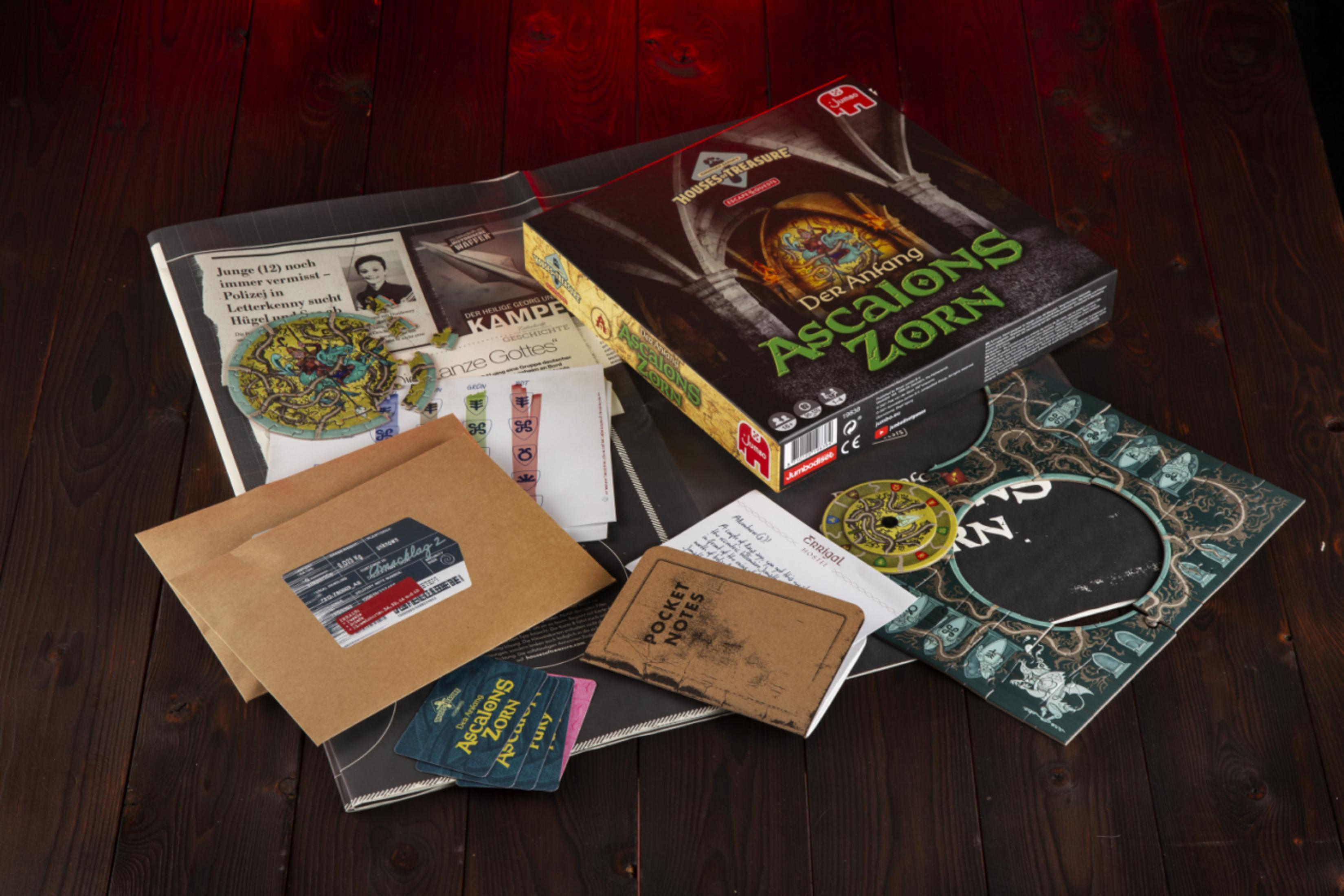 Verschiedene Gegenstände eines Brettspiels sind auf einer Holzoberfläche verstreut, darunter Karten und eine Spielbox.