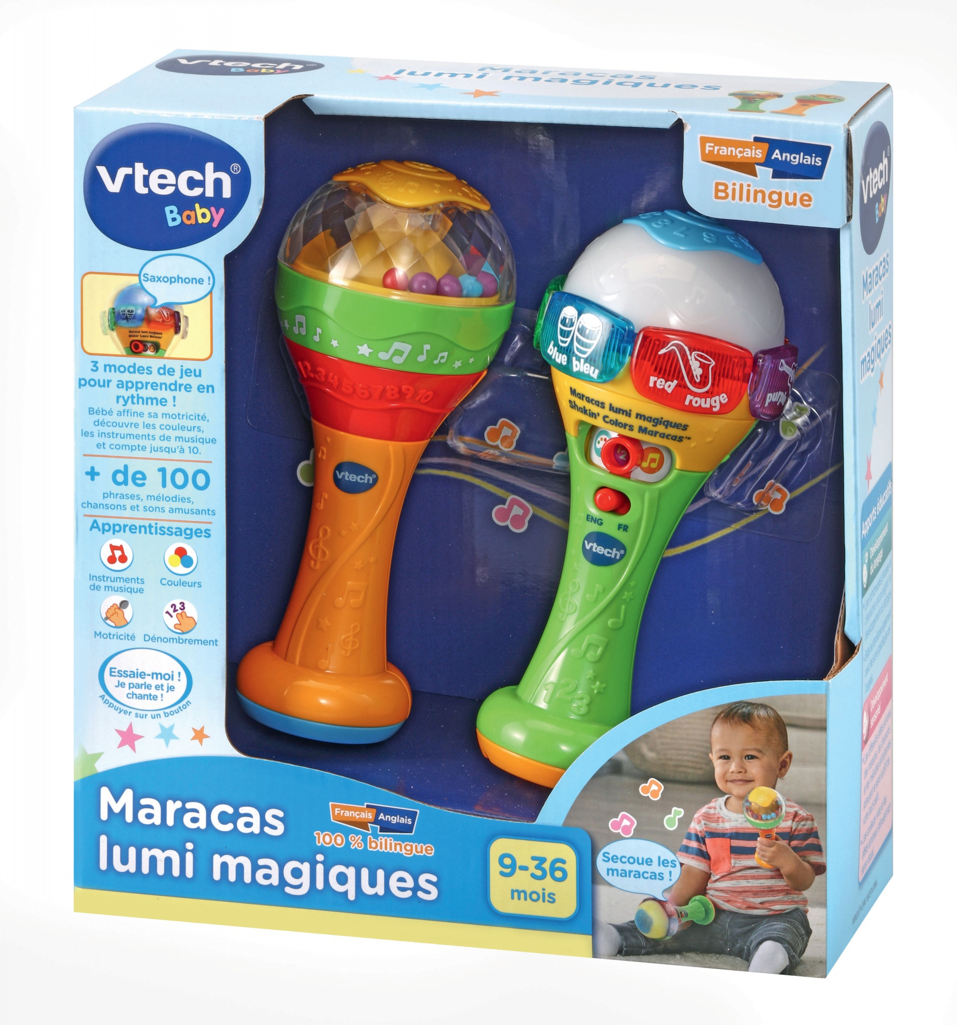 Ein Spielzeug in der Box mit zwei Maracas, einer orangefarbenen und einer grünen, mit einem Baby im Hintergrund.