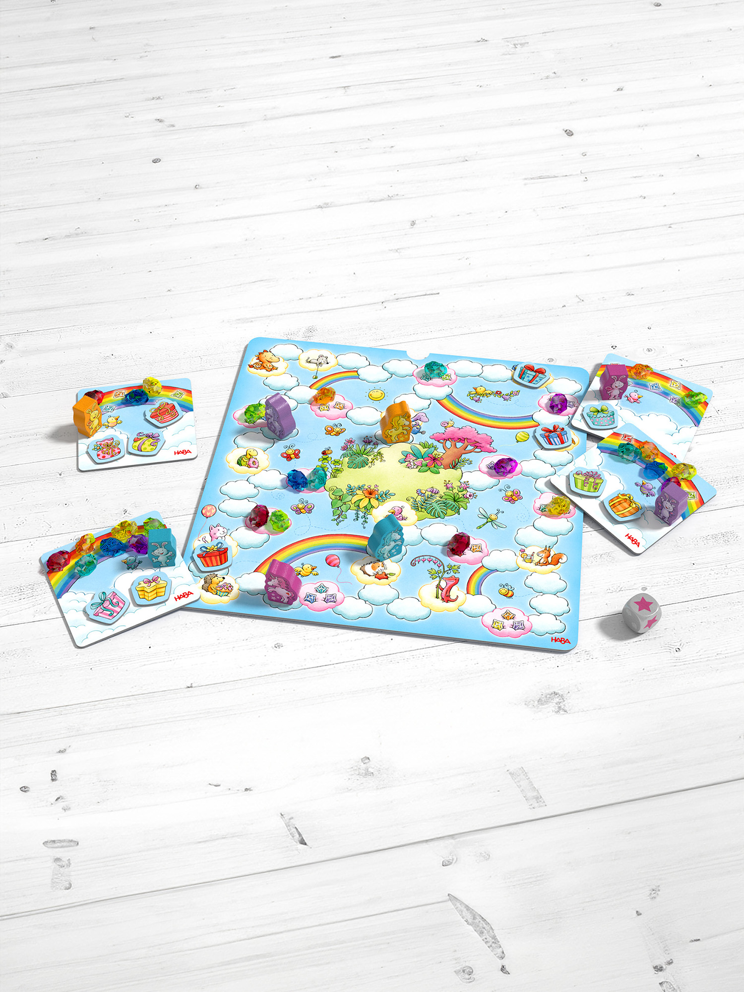 Brettspiel mit Einhorn-Illustrationen, Würfeln und Spielsteinen auf weißer Holzoberfläche.