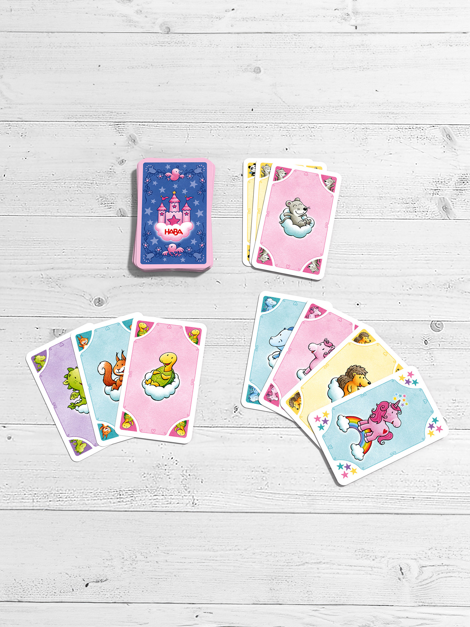 Spielkarten mit Cartoonfiguren auf weißem Holzgrund. Karten sind gefächert.