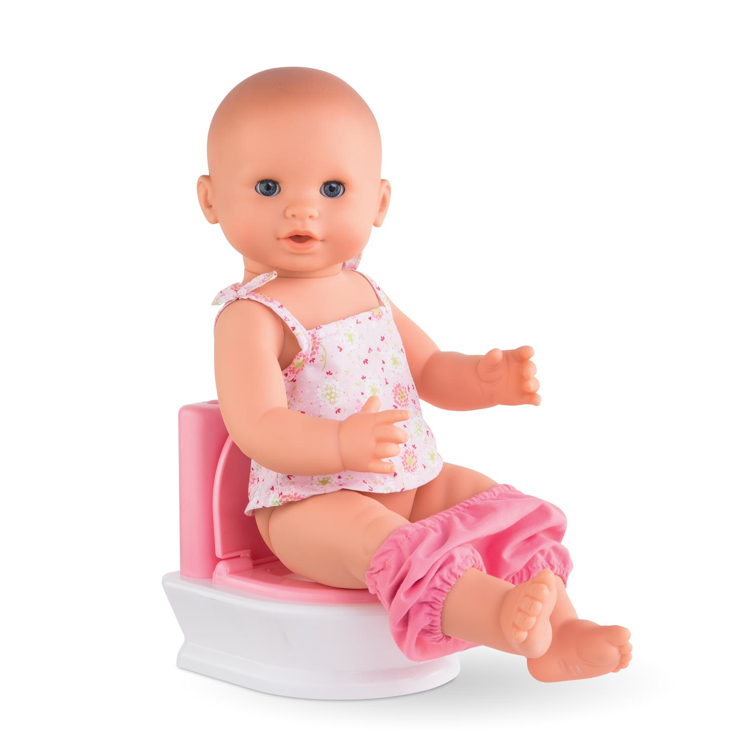 Lalka siedząca na różowym nocniku, ubrana w różowe ubranka.