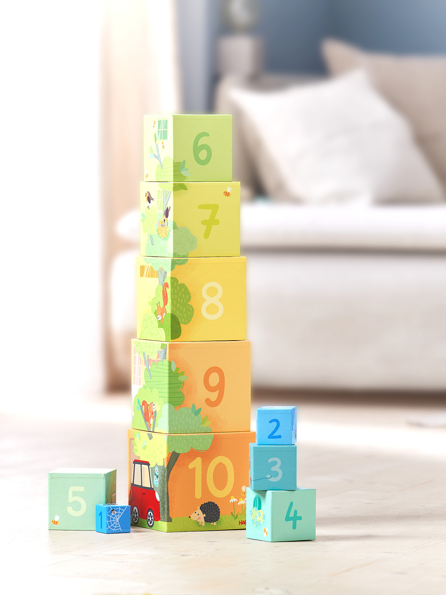 Stapelspielzeugblöcke in einem Turm mit Zahlen und Illustrationen, in einem Raum mit einem Sofa angeordnet.