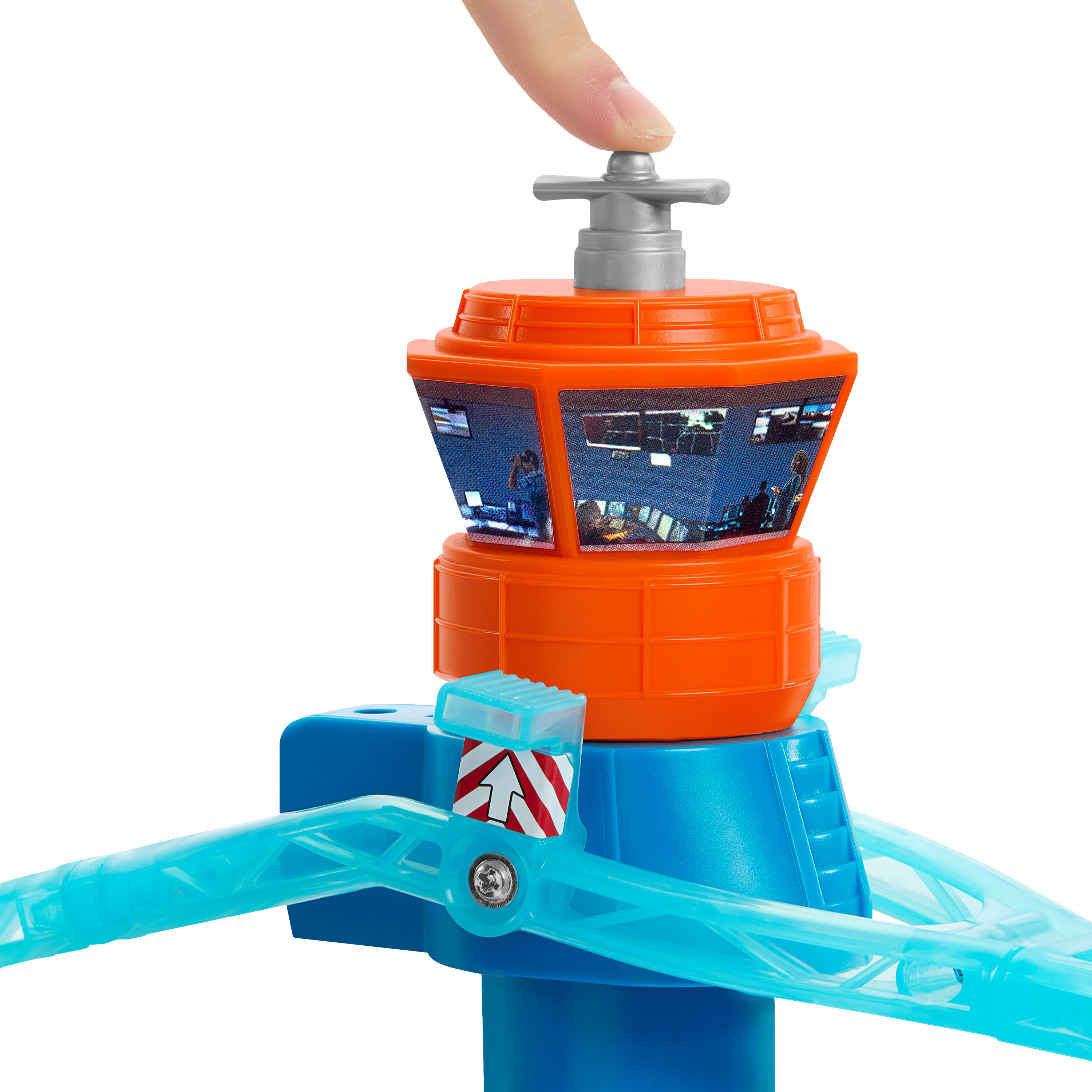 Ein Spielzeug-Fluglotsenturm. Ein Finger drückt einen grauen Hebel oben auf einem orangefarbenen Turm.