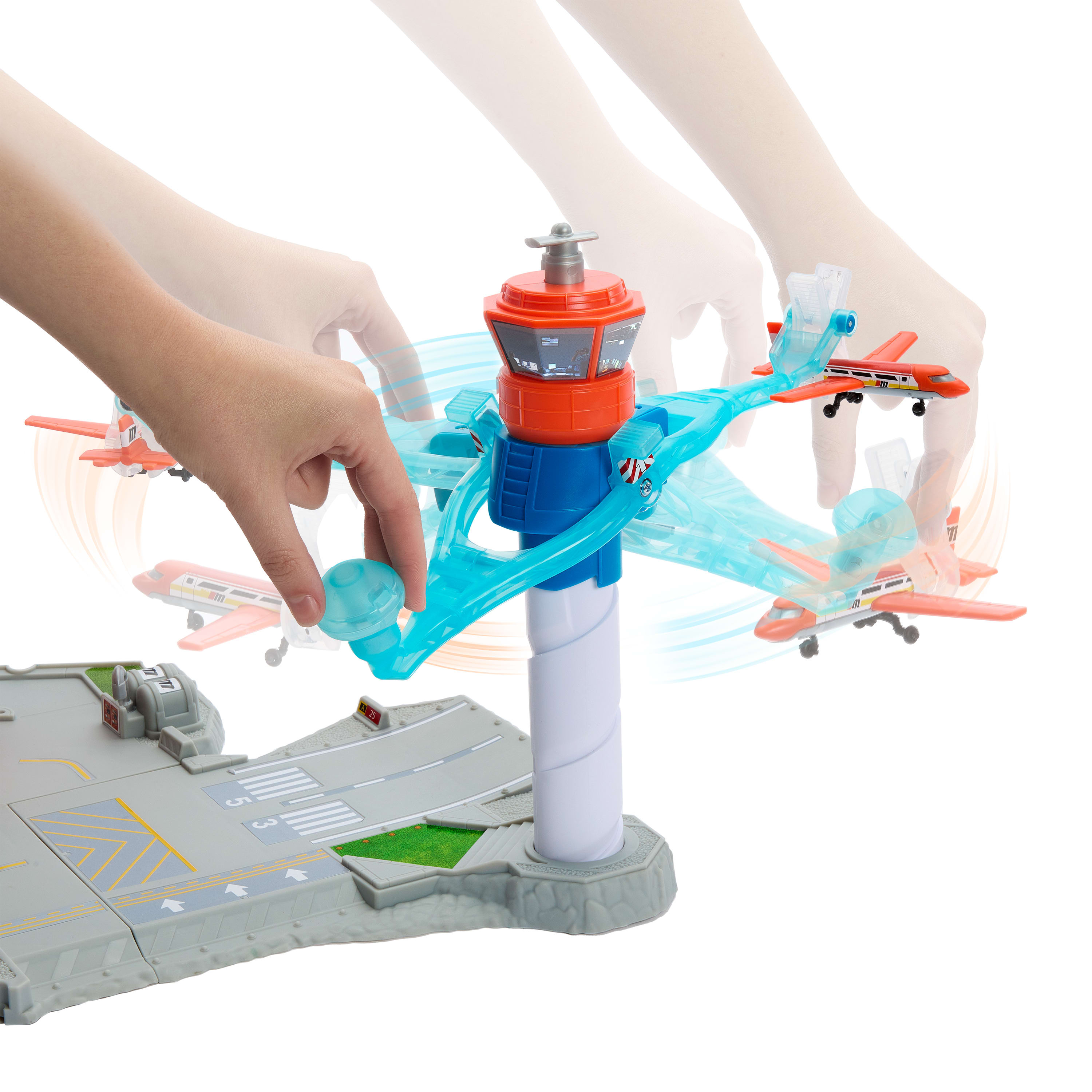 Spielzeugflughafen mit Flugzeugen und Kontrollturm, der von Händen manipuliert wird.