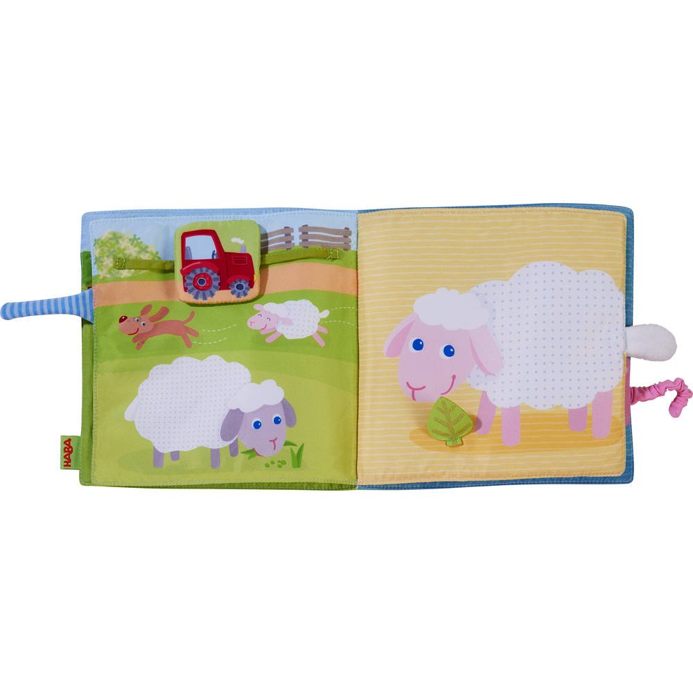 Otwarta książka ze sceną z farmy, z owcami, traktorem i psem.