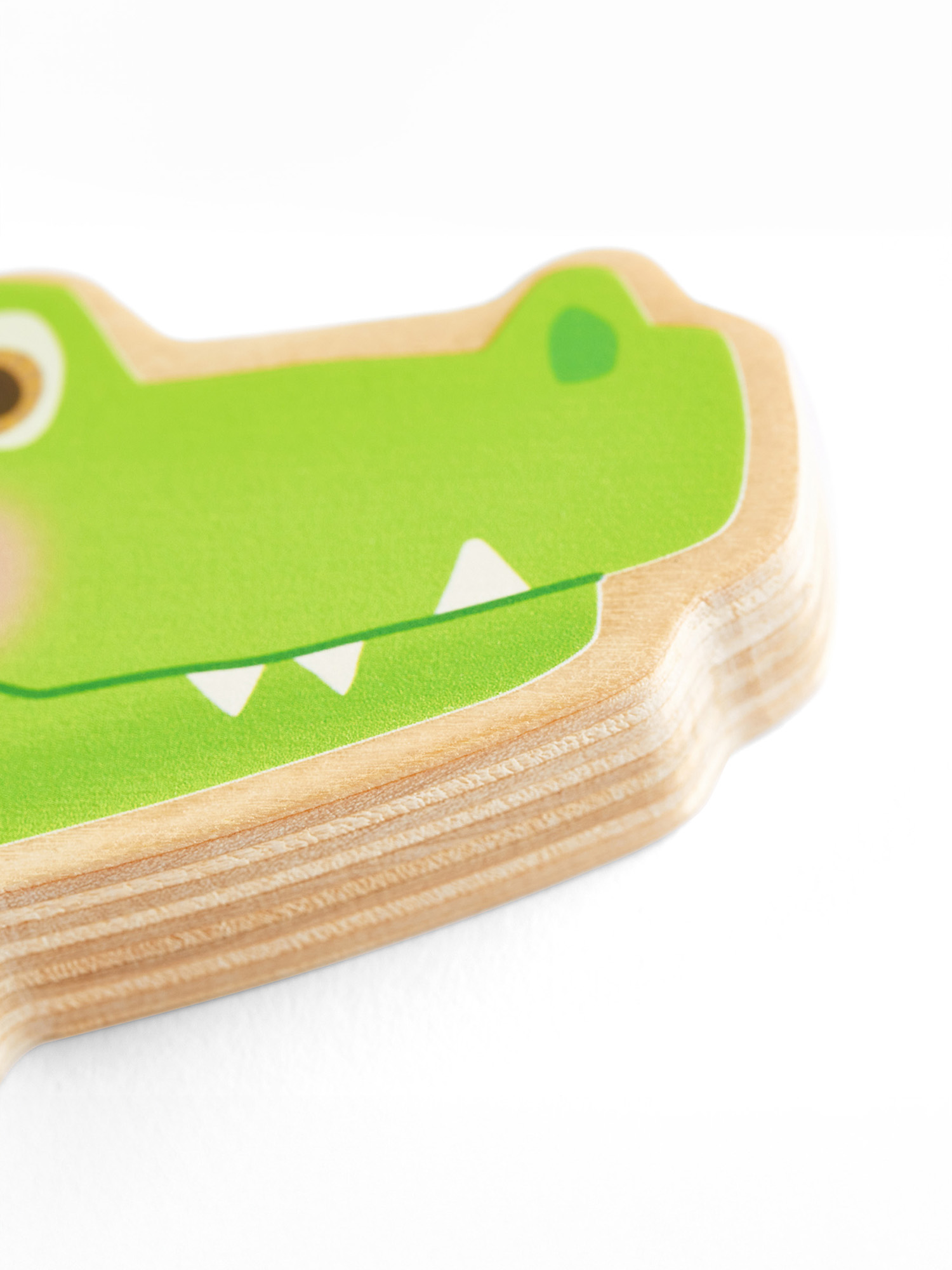 Nahaufnahme des Kopfes eines grünen Alligators auf einem Holzspielzeug. Weißer Hintergrund.