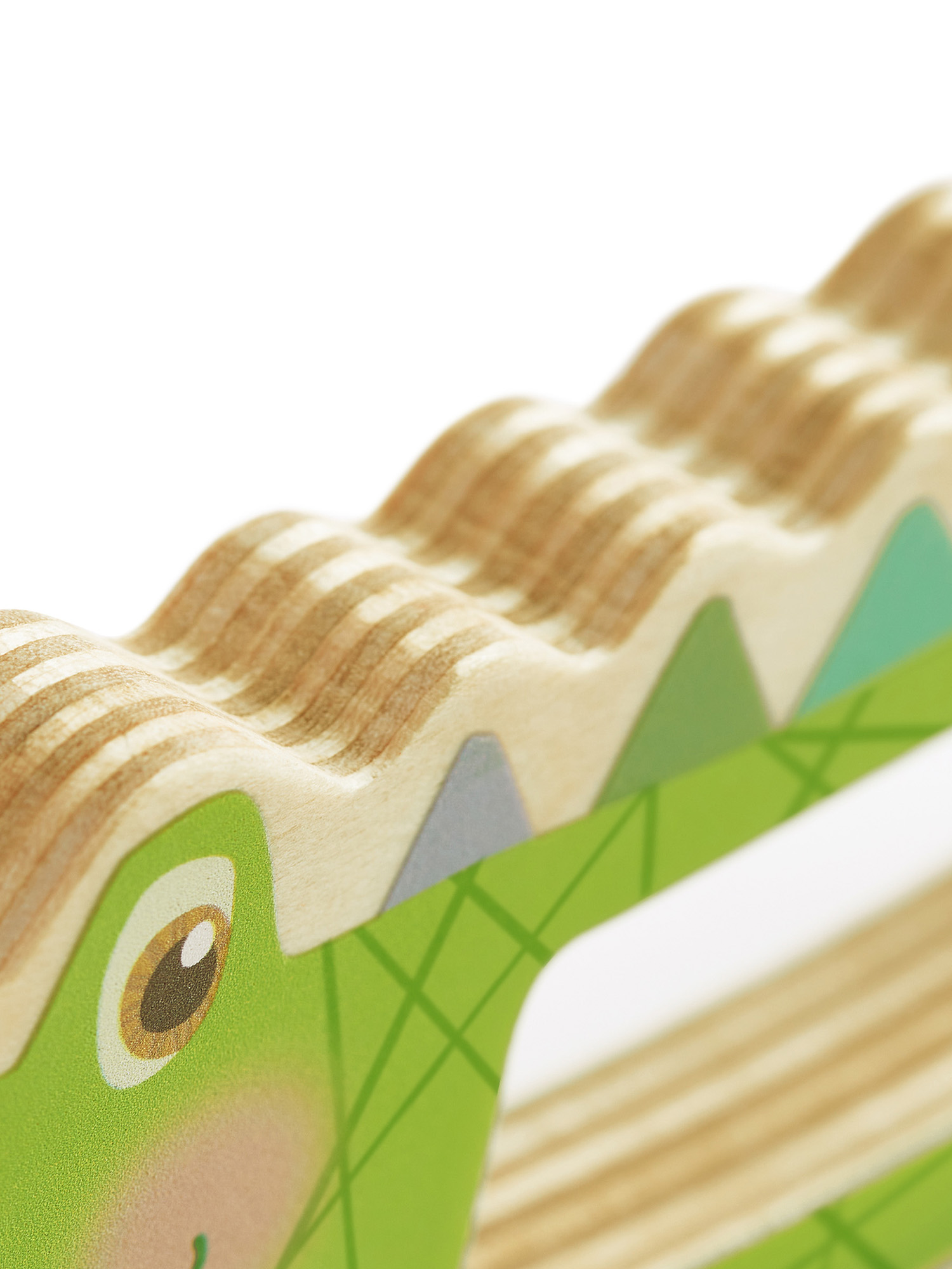 Nahaufnahme eines Holz-Alligator-Spielzeugs. Das Spielzeug hat grün bemalte Details. Weißer Hintergrund.