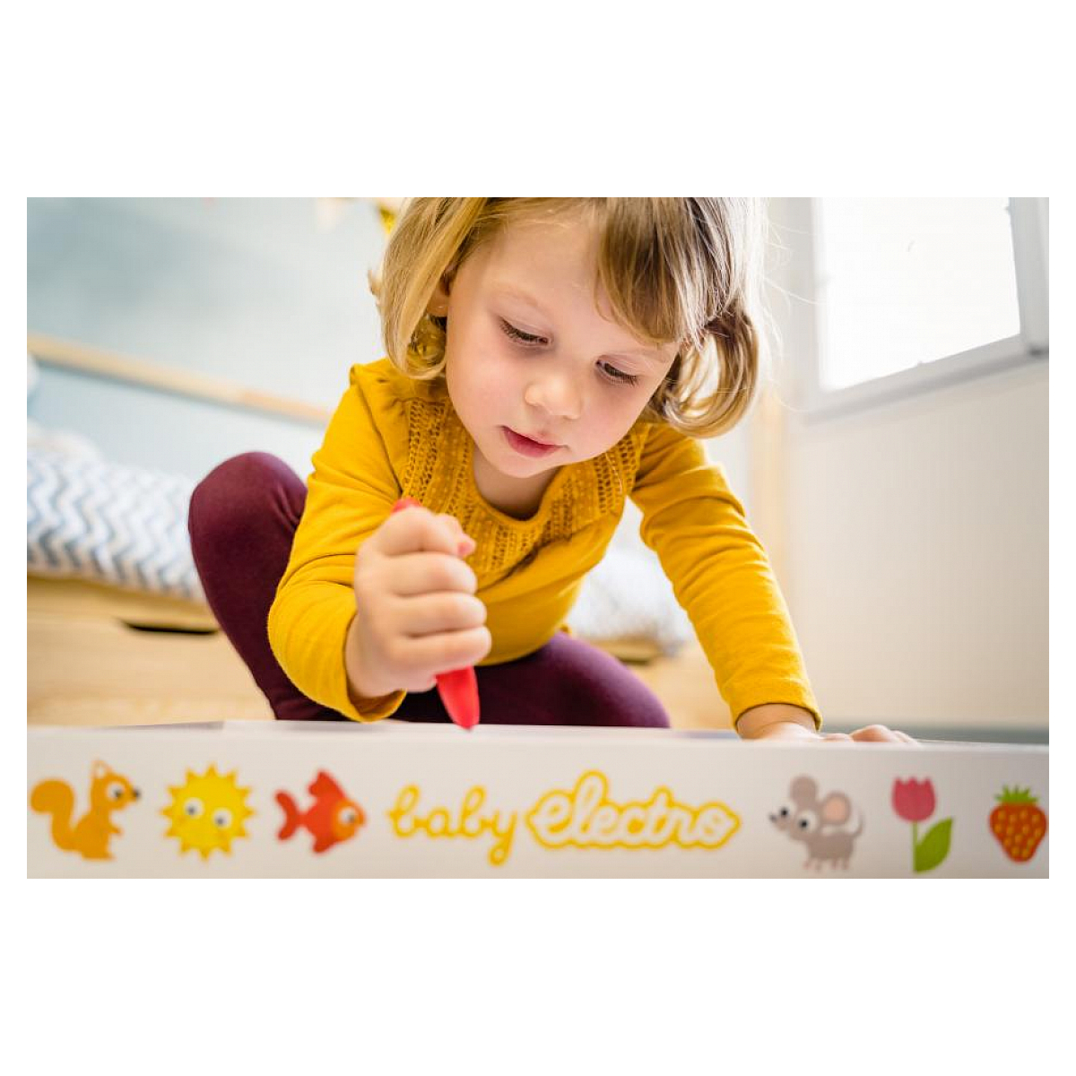Mała dziewczynka rysująca czerwoną kredką na tablicy Baby Electro.