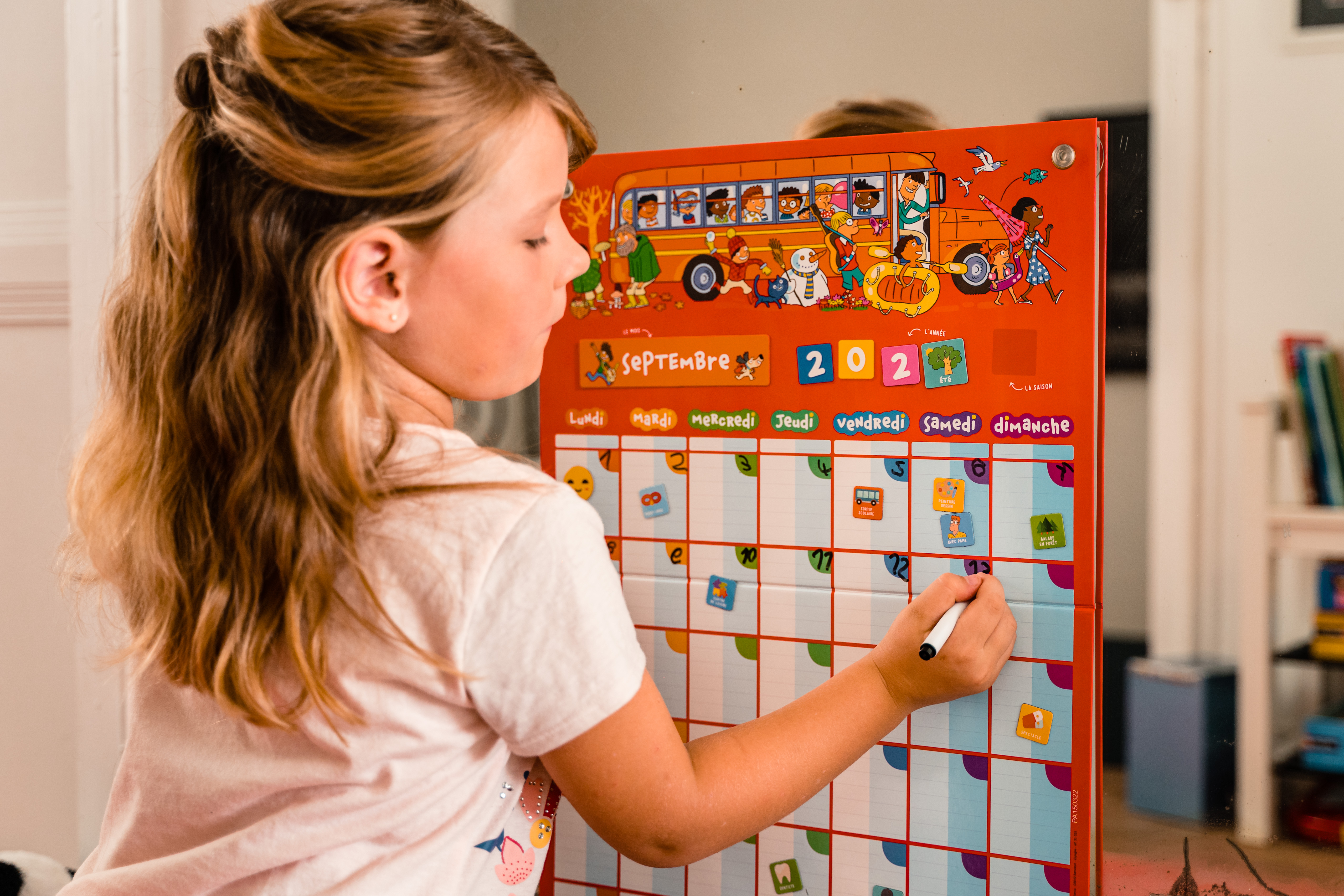 Młoda dziewczyna rysuje na czerwonym kalendarzu ściennym, otwartym na wrzesień 2021 r., markerem.