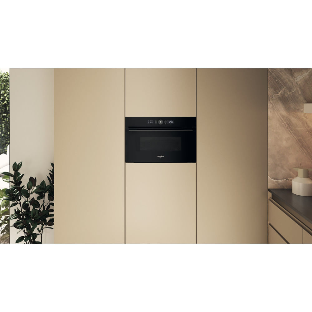 Un forno a microonde Whirlpool da incasso in un mobile da cucina con uno schema di colori beige.