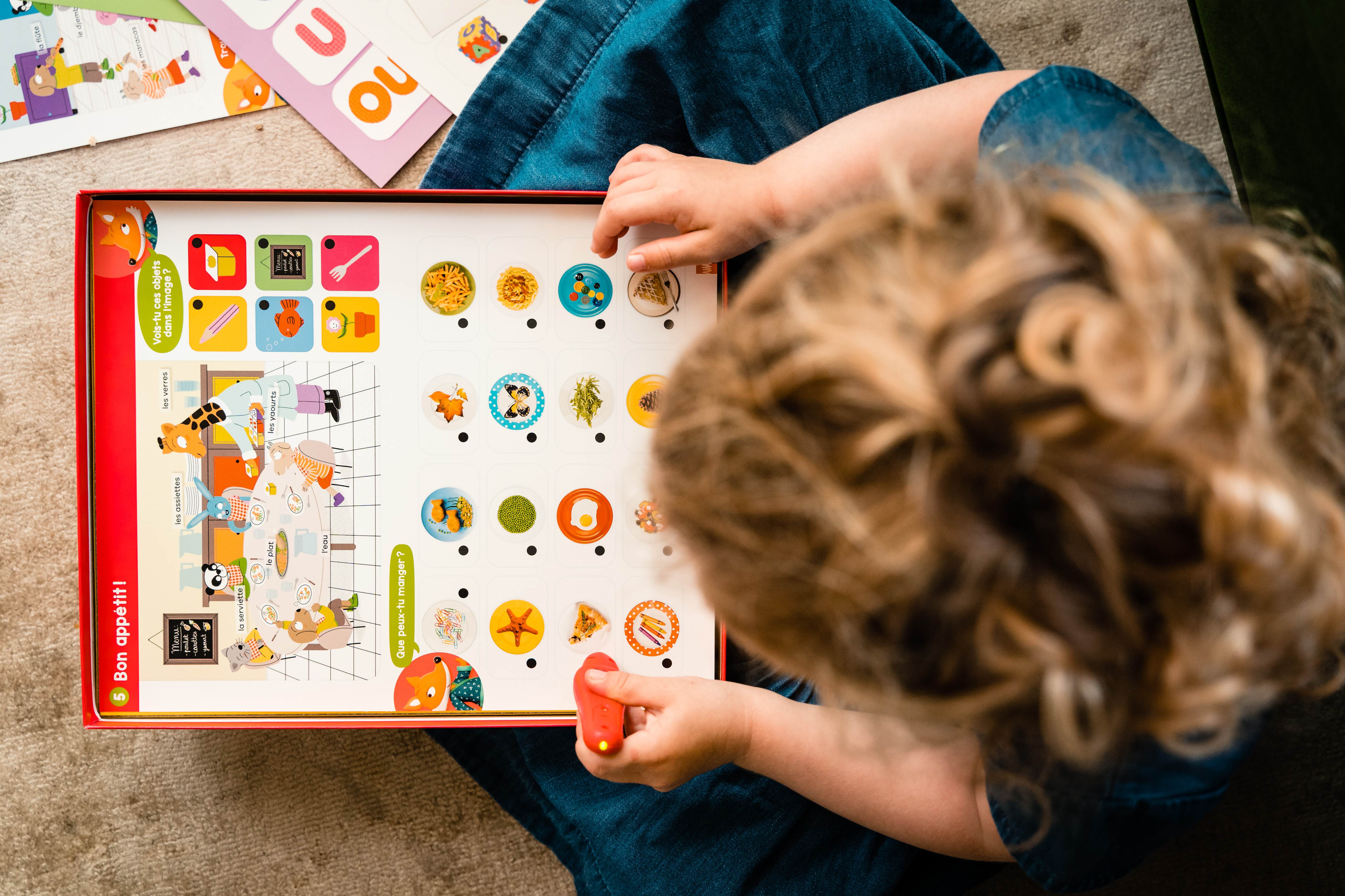 Dziecko patrzy na grę planszową z rysunkami jedzenia. Dziecko siedzi i patrzy na grę.