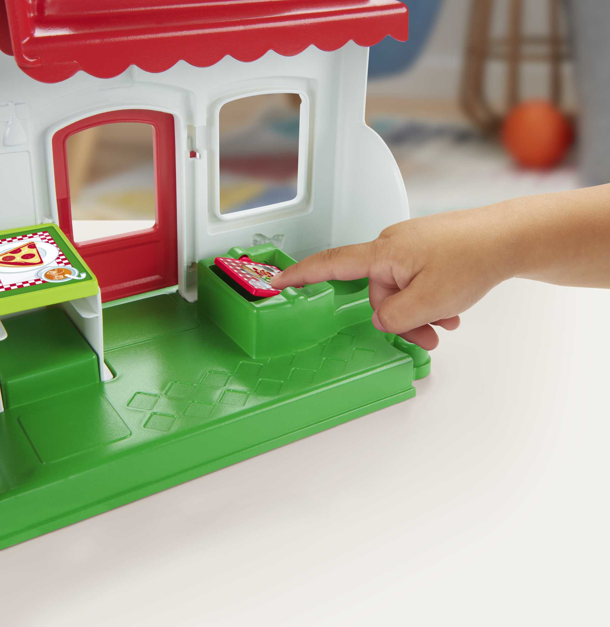 La mano di un bambino che raggiunge una pizza giocattolo in un playset pizzeria.