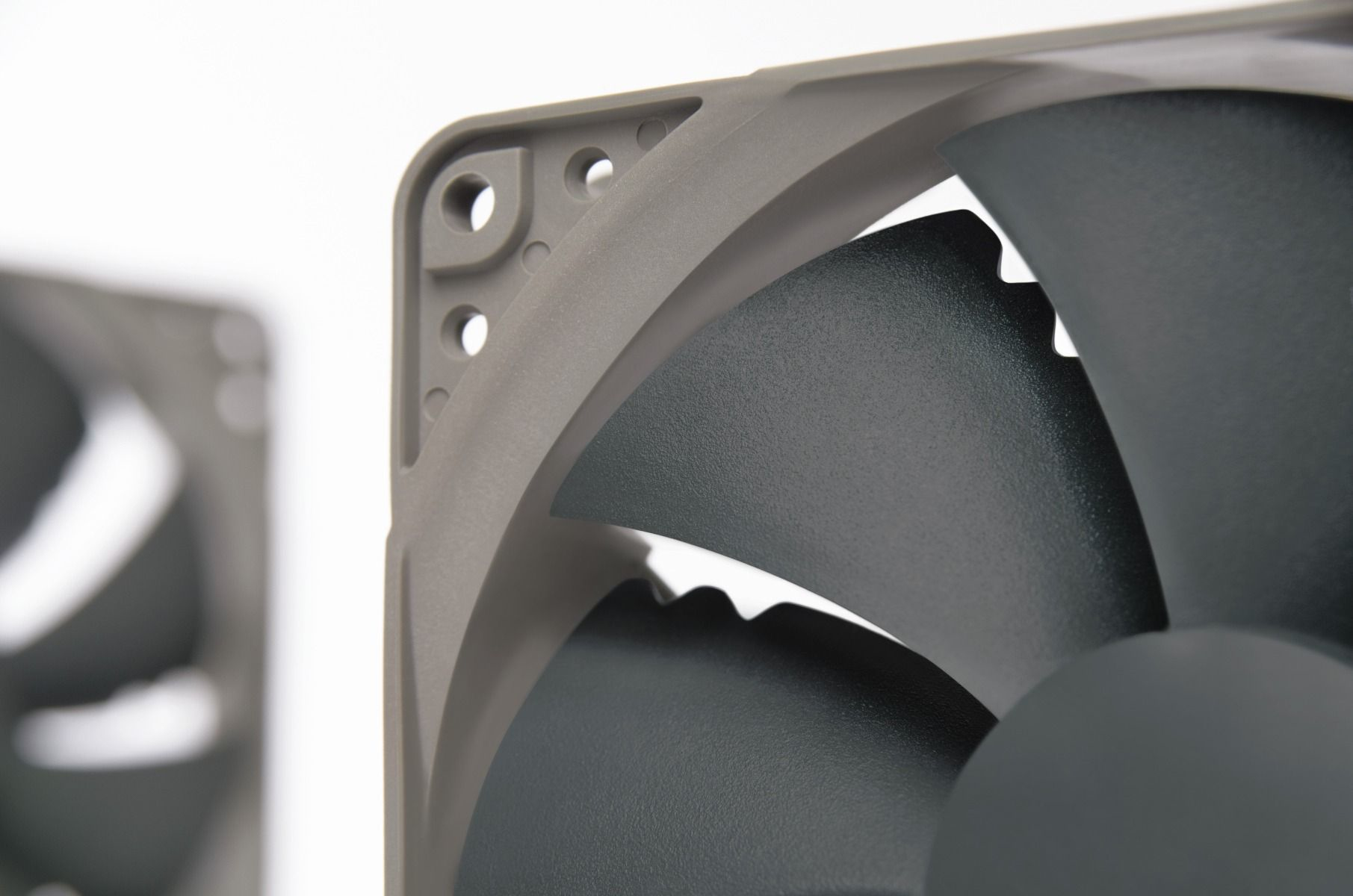 Gros plan sur deux pales de ventilateur d'ordinateur grises. Le cadre est également gris. Fond blanc.