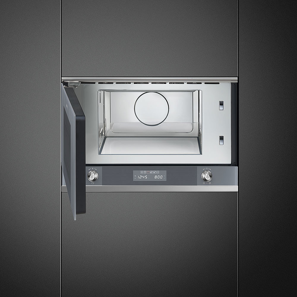 Forno a microonde, porta aperta. Visualizza l'ora. Finitura argentata. In una parete grigio scuro.