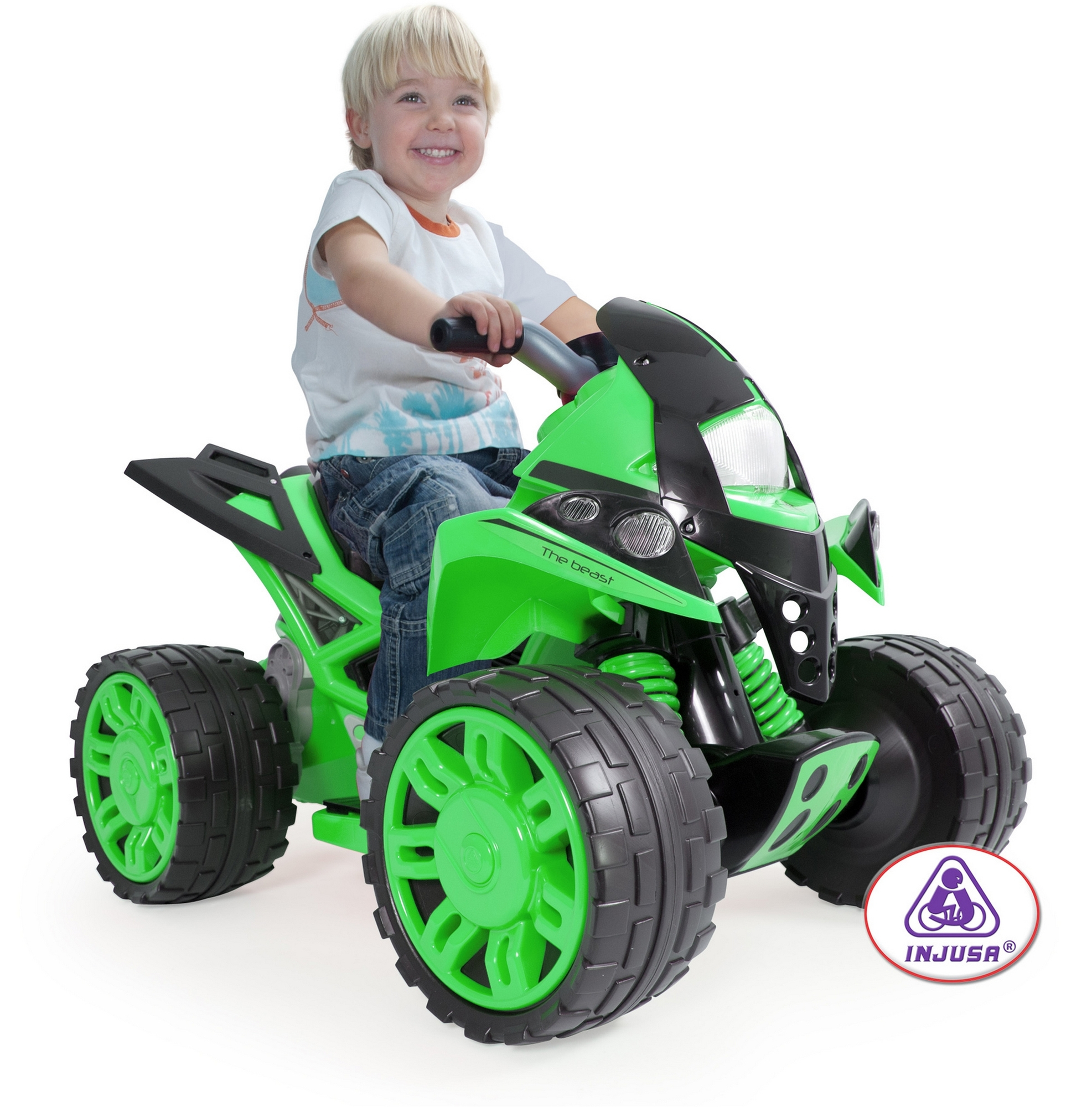 Dziecko jedzie na zielono-czarnym quadzie. Dziecko się uśmiecha. Quad stoi na białej powierzchni.