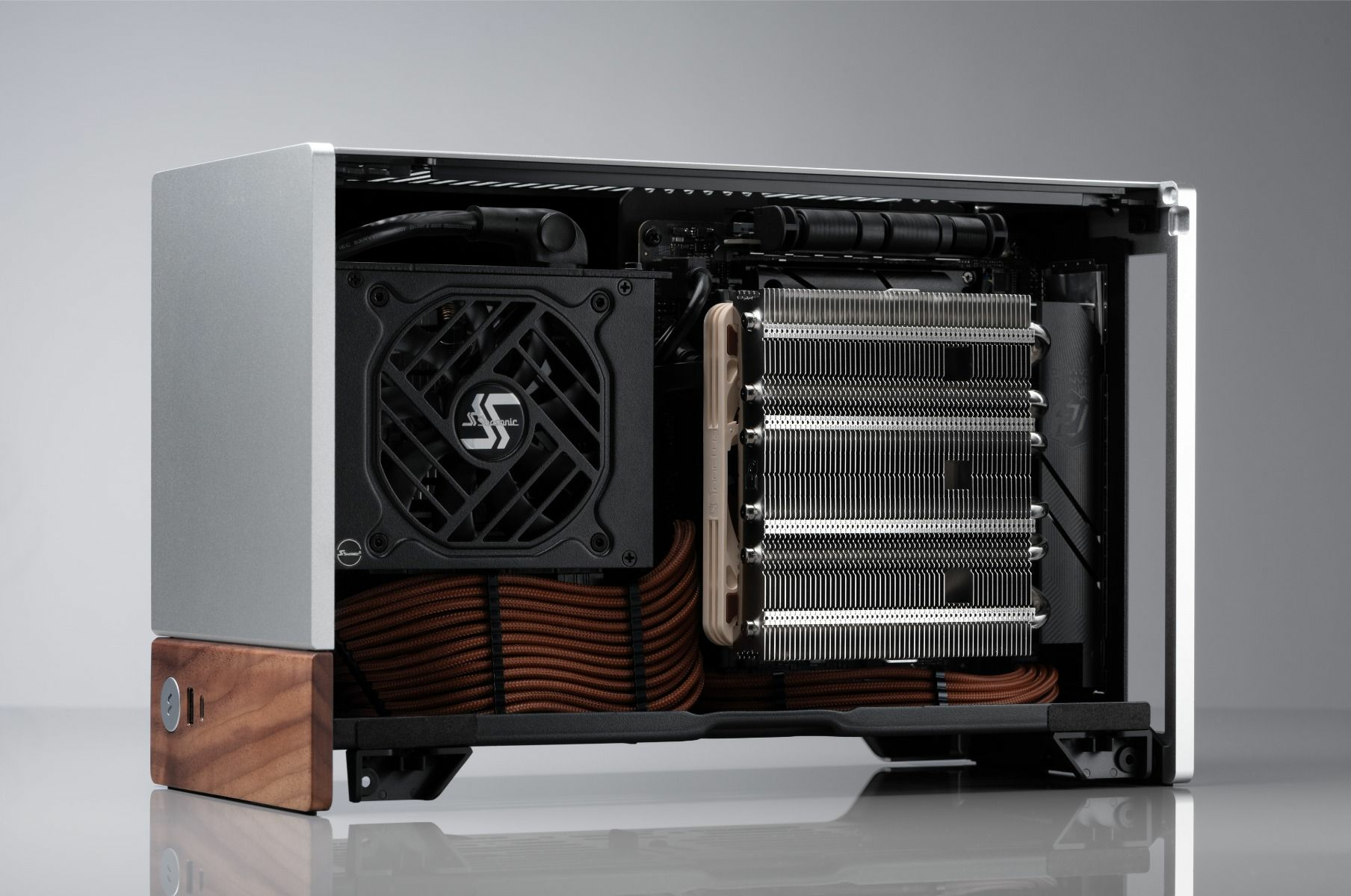 Computer case interior showing components, including a fan, cooling system, and wiring. Silver and brown.