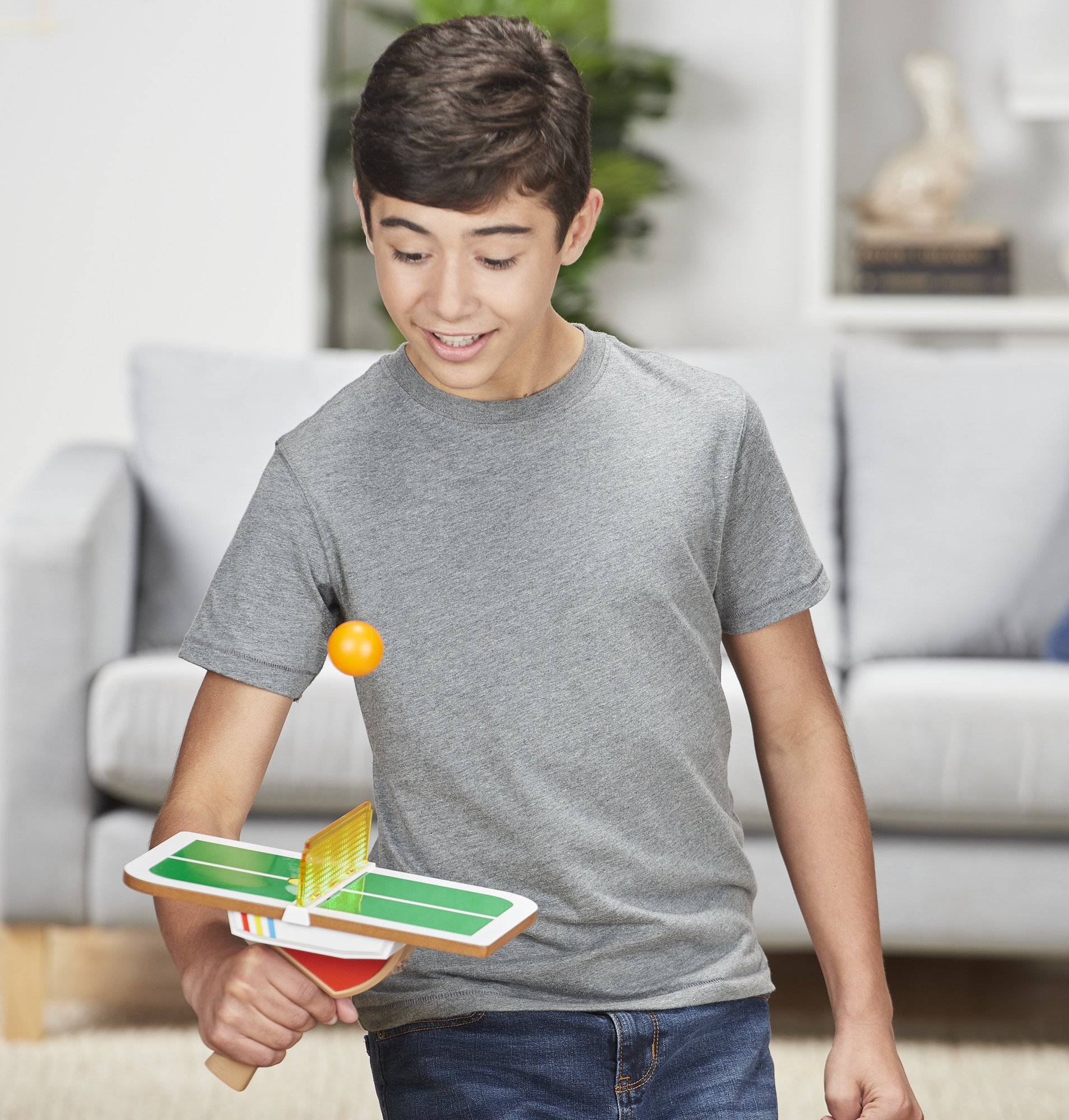 Un giovane che gioca a ping pong con una piccola rete e una palla in mano.