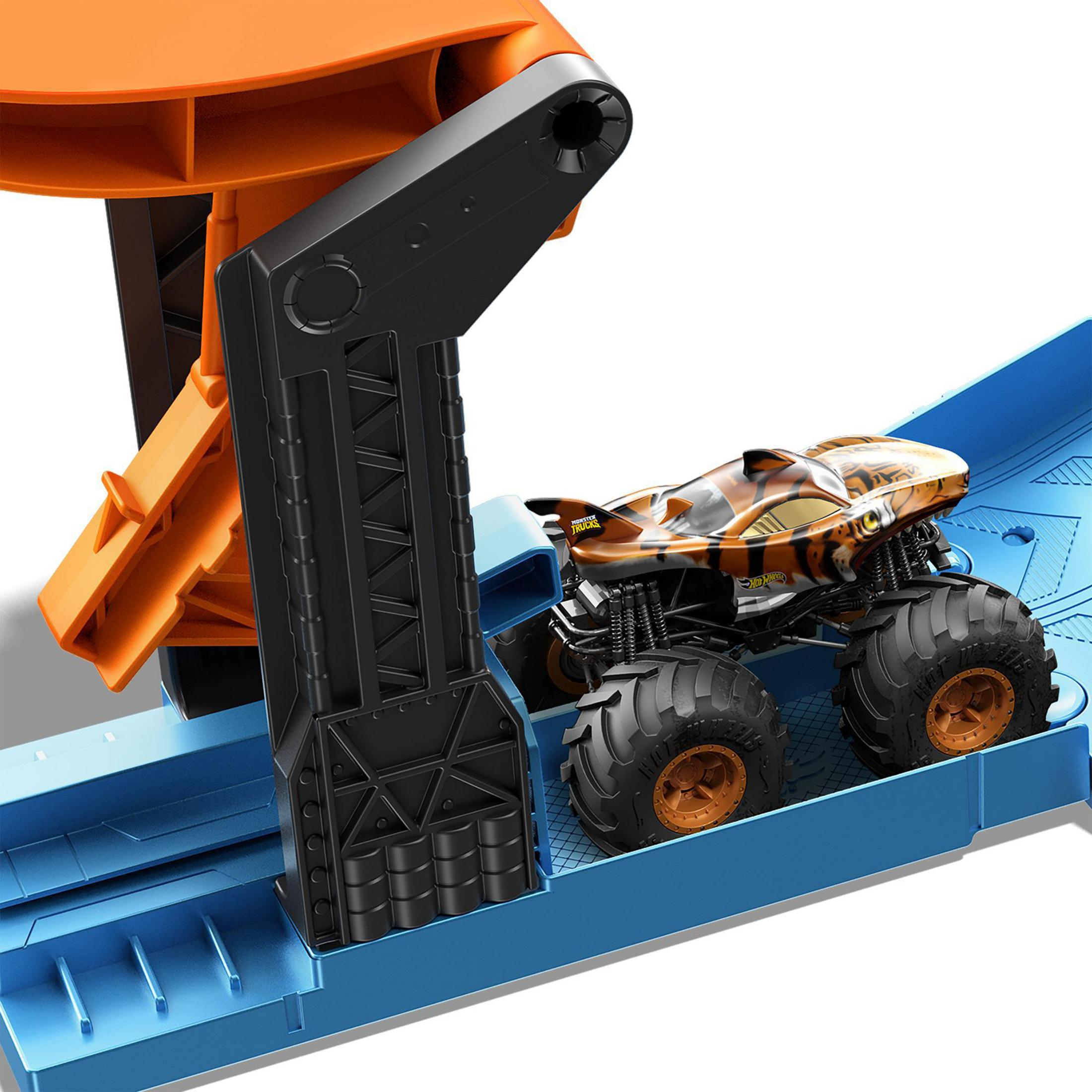 Zabawkowy monster truck na niebieskim torze z pomarańczowym mechanizmem startowym.