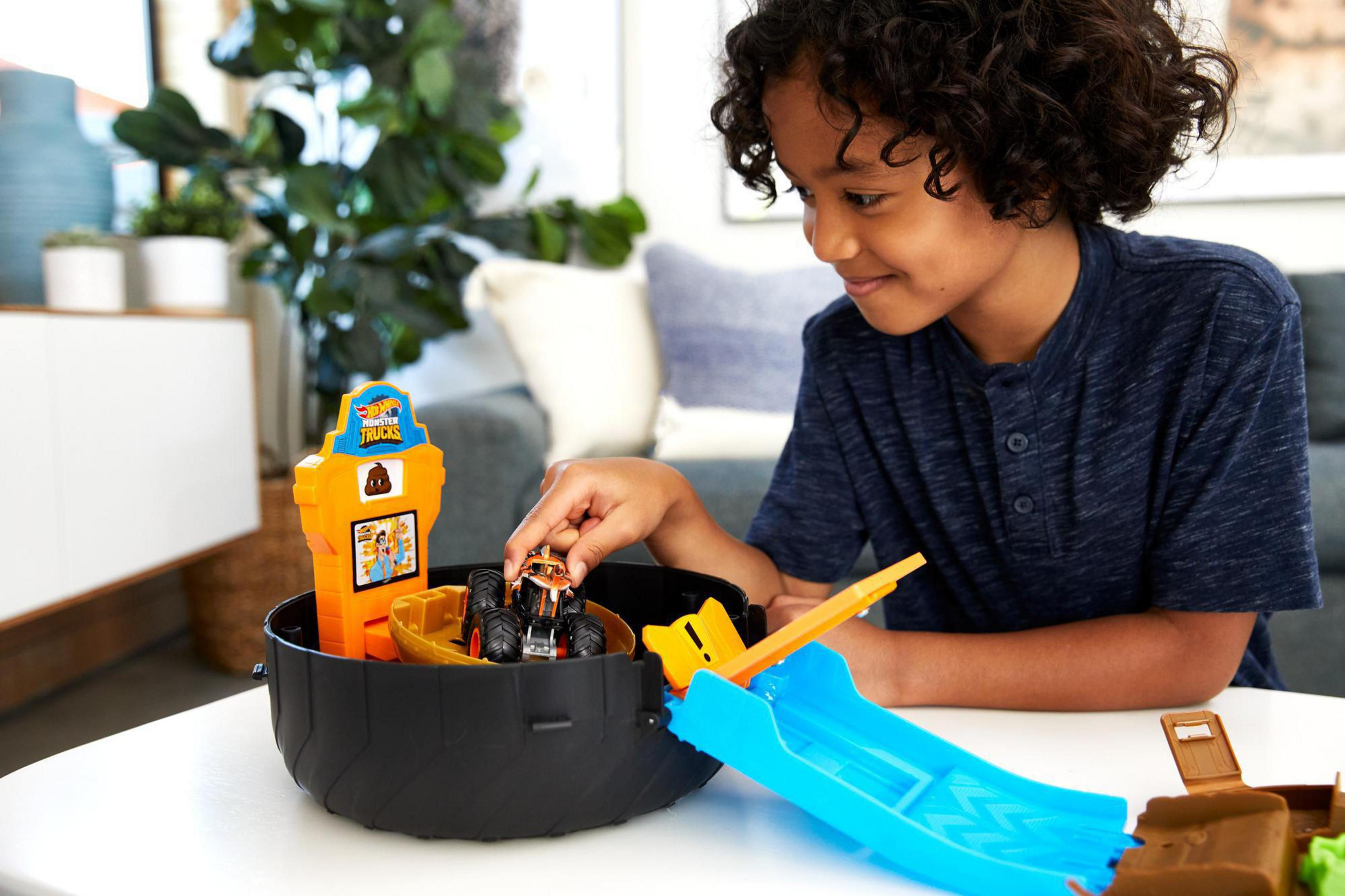 Chłopiec bawi się zestawem zabawek z ciężarówkami. Zestaw zawiera tor, rampę i małą ciężarówkę potwora.