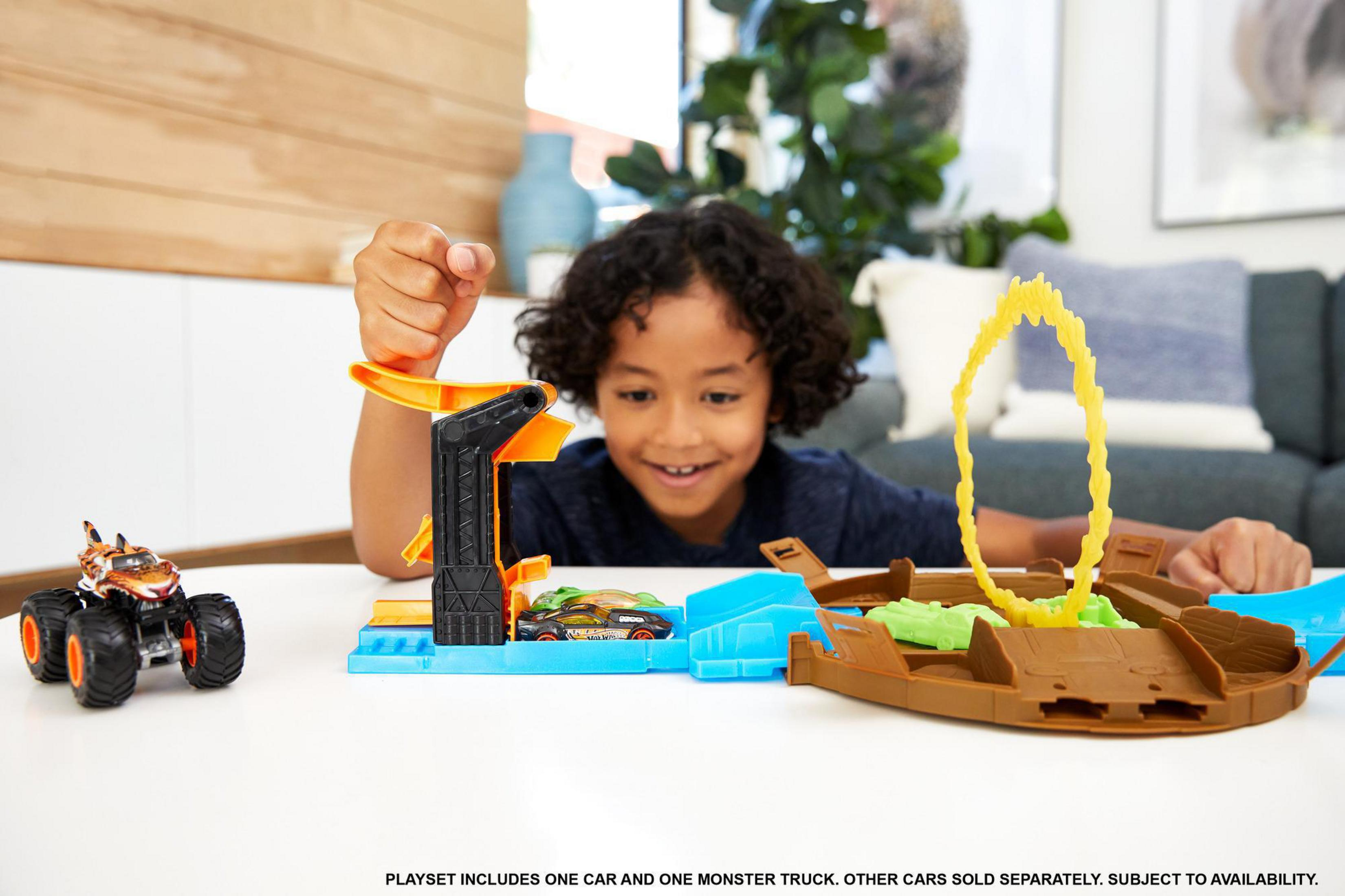 Dziecko bawiące się zestawem Hot Wheels Monster Trucks na stole.