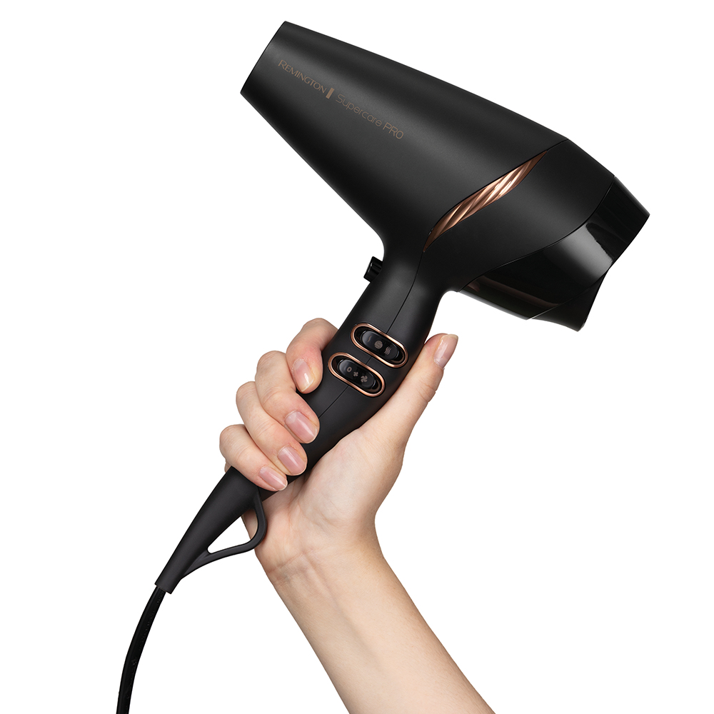 Siyah bir Remington Supercare Pro saç kurutma makinesi, bir el tarafından tutuluyor, beyaz bir arka plan üzerinde.