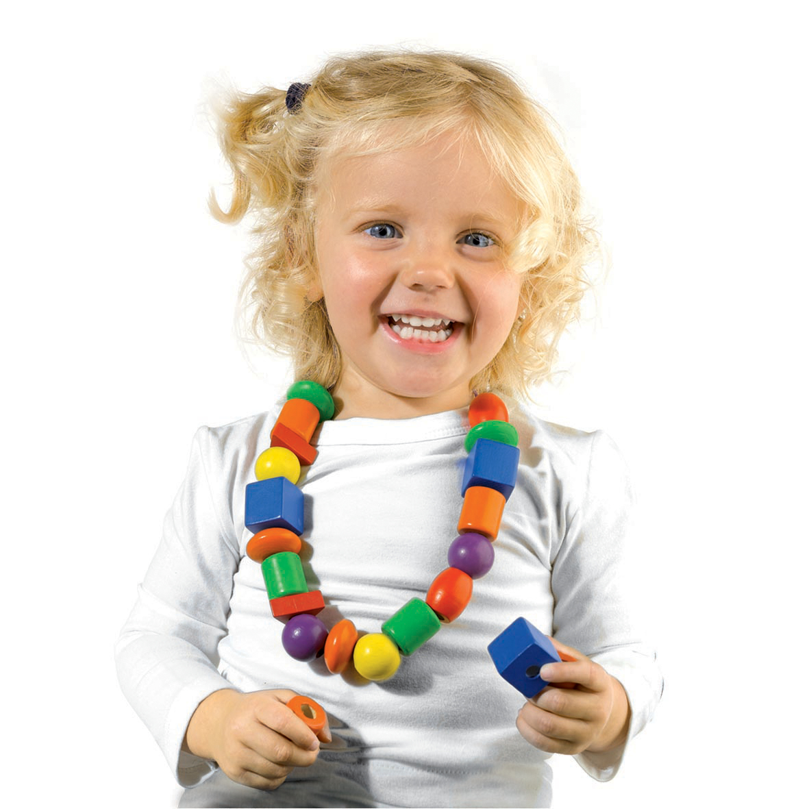 Młoda dziewczyna z kolorowym naszyjnikiem z koralików, trzymająca drewniany klocek. Uśmiechnięta.