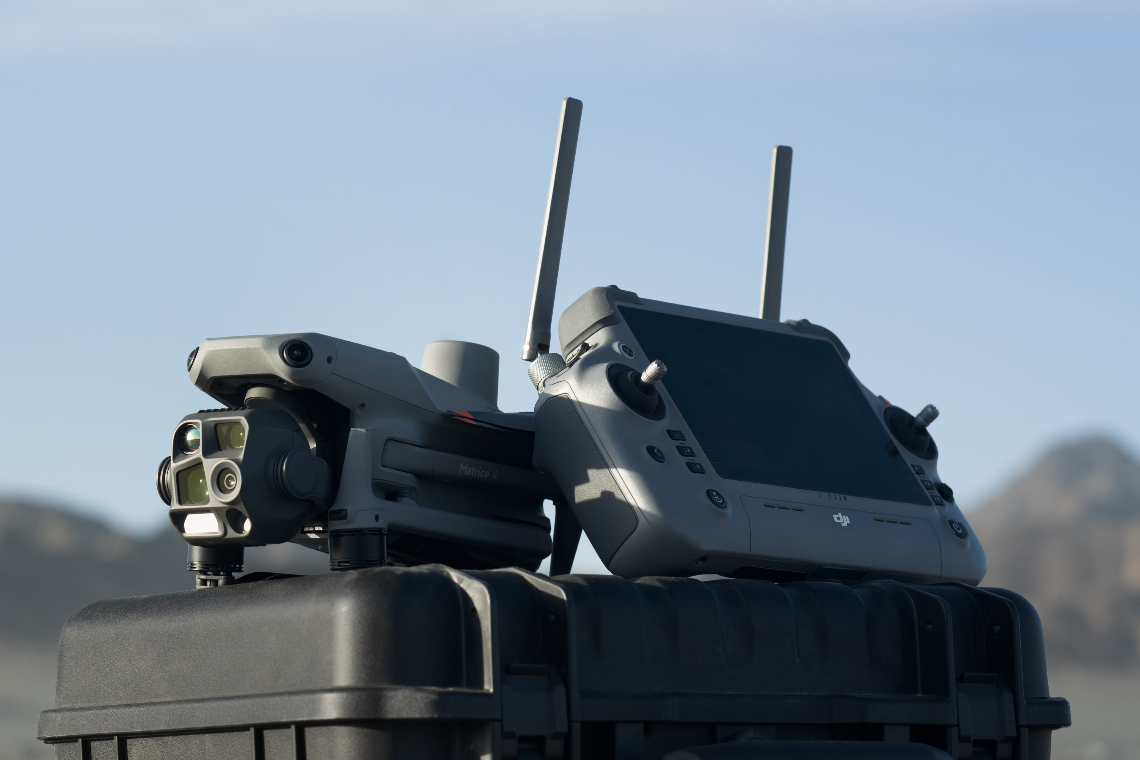 Dron DJI i kontroler na czarnej walizce, na zewnątrz z rozmytym tłem.