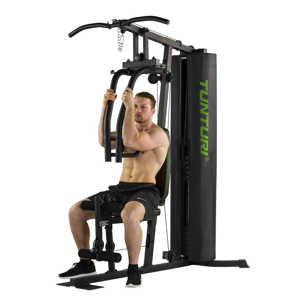 Un uomo sta usando una macchina da palestra domestica. La macchina è nera e verde, con un pacco pesi nero.