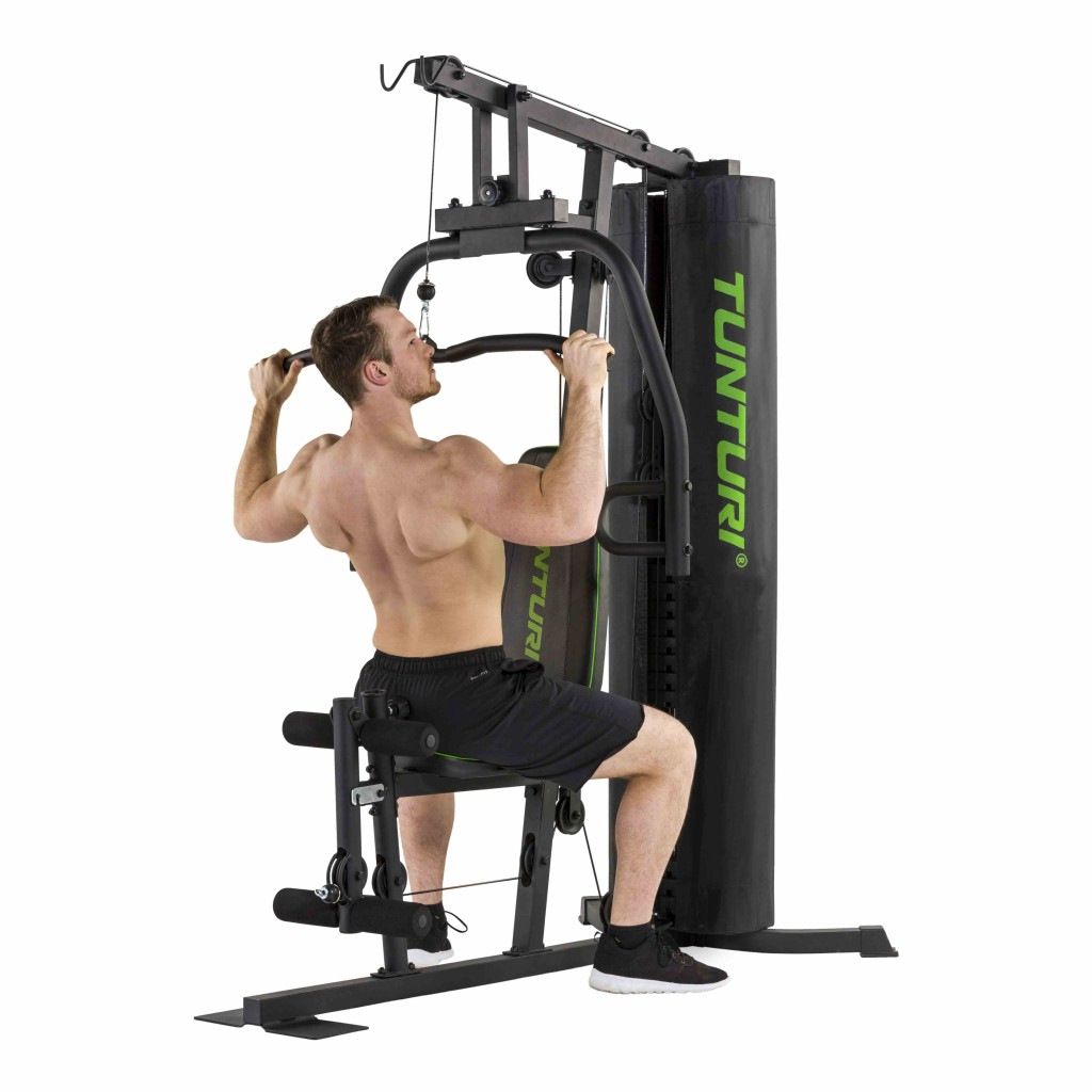 Un uomo sta usando una macchina da palestra domestica. Sta tirando giù una sbarra da seduto. La macchina è nera e verde.