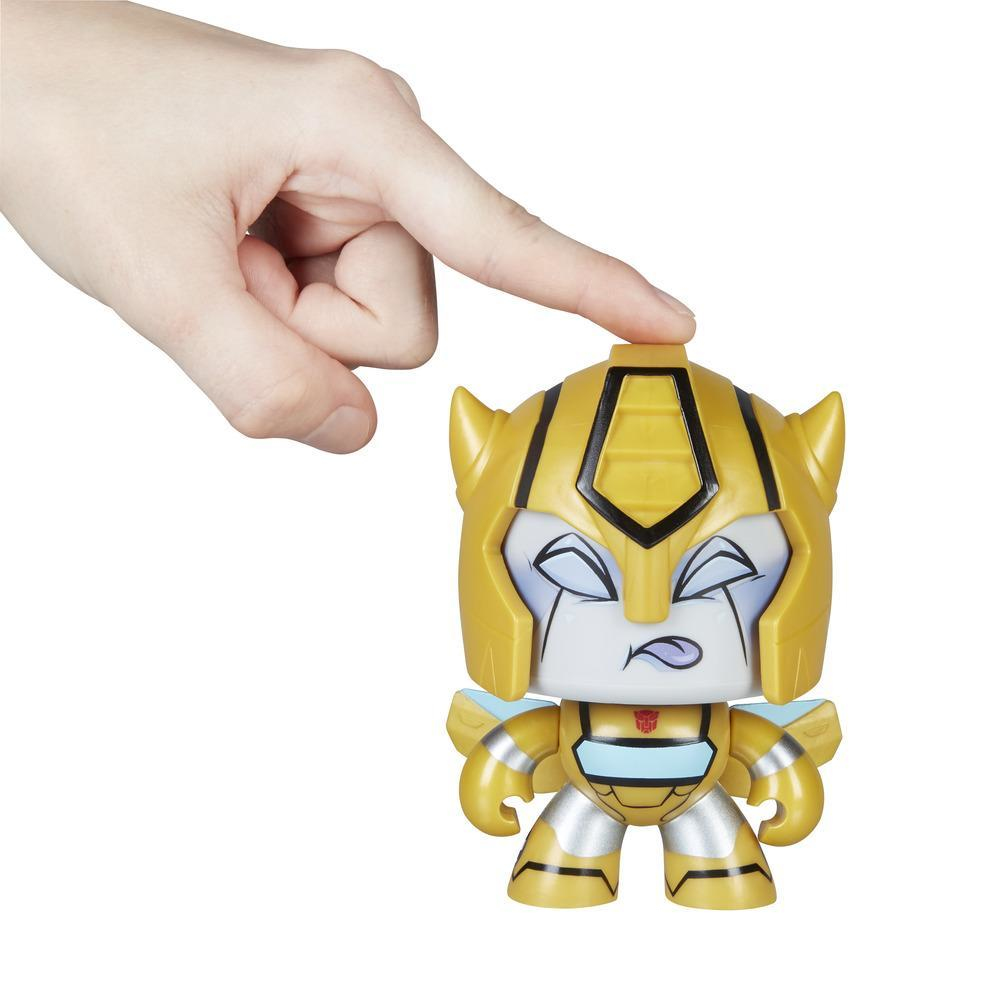 Mano che indica il giocattolo Bumblebee, giallo e nero, bocca aperta, sfondo bianco.