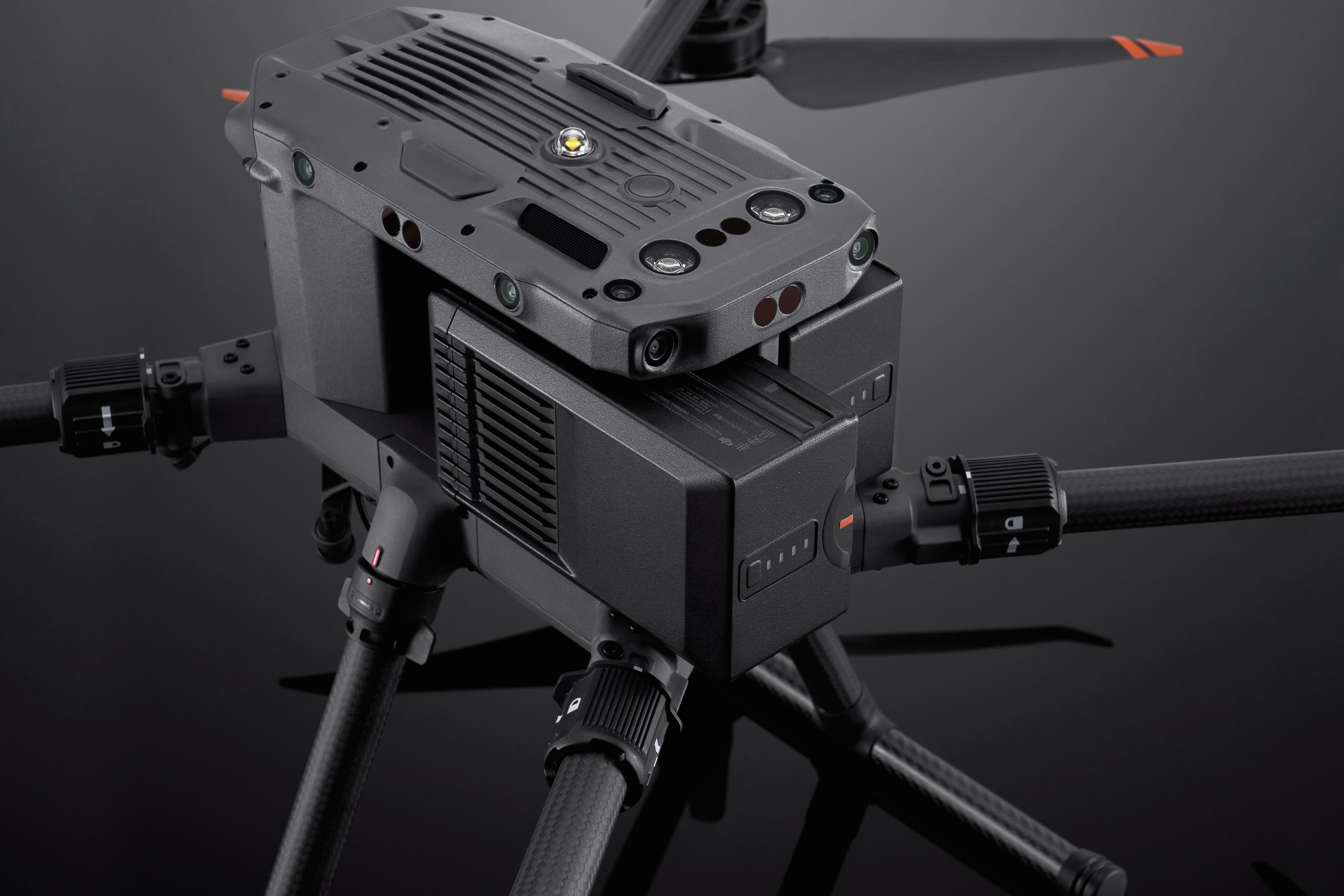 Drone con più telecamere, colore nero, eliche visibili. Sfondo nero.