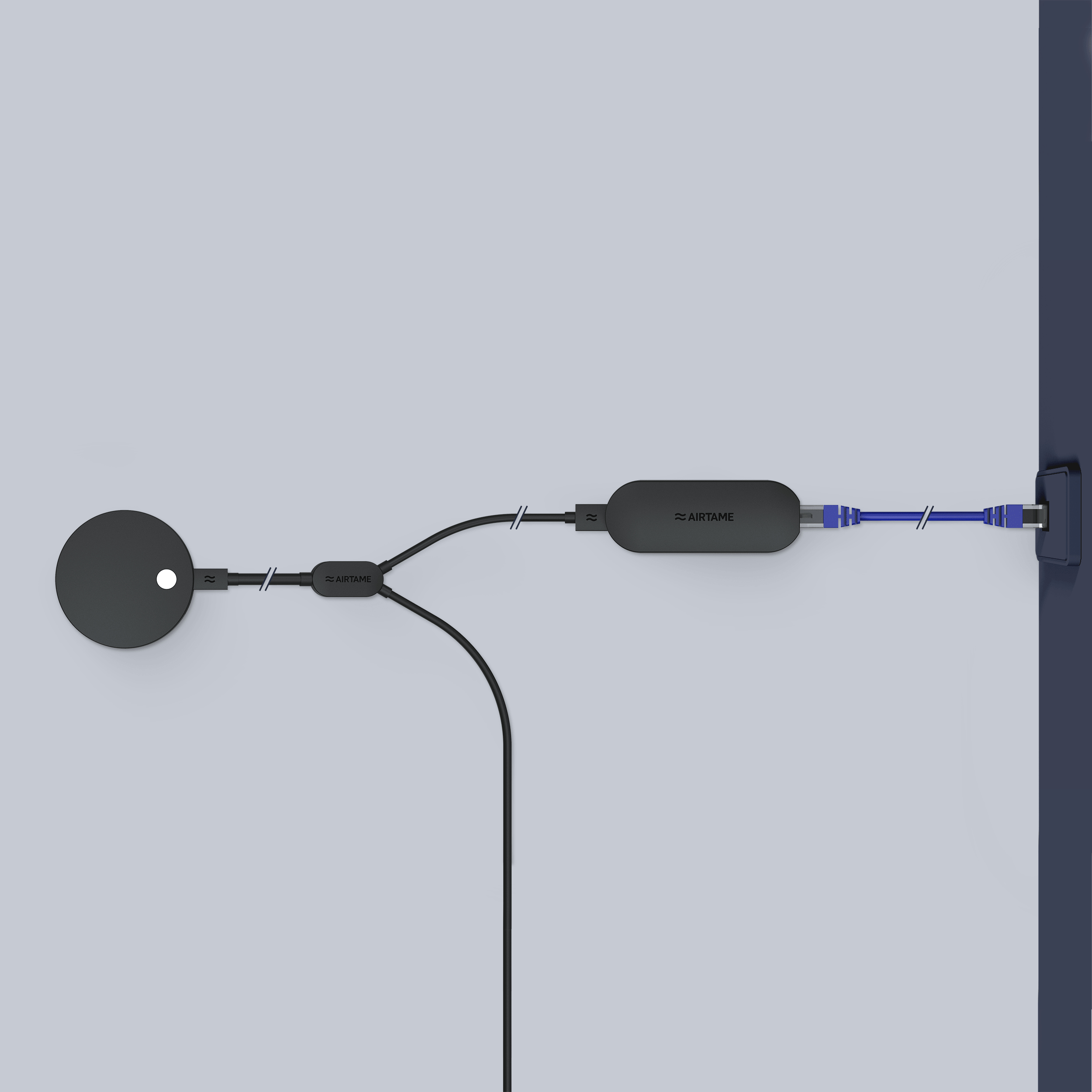 Black Airtame device with cord connected to a wall and a circular object.