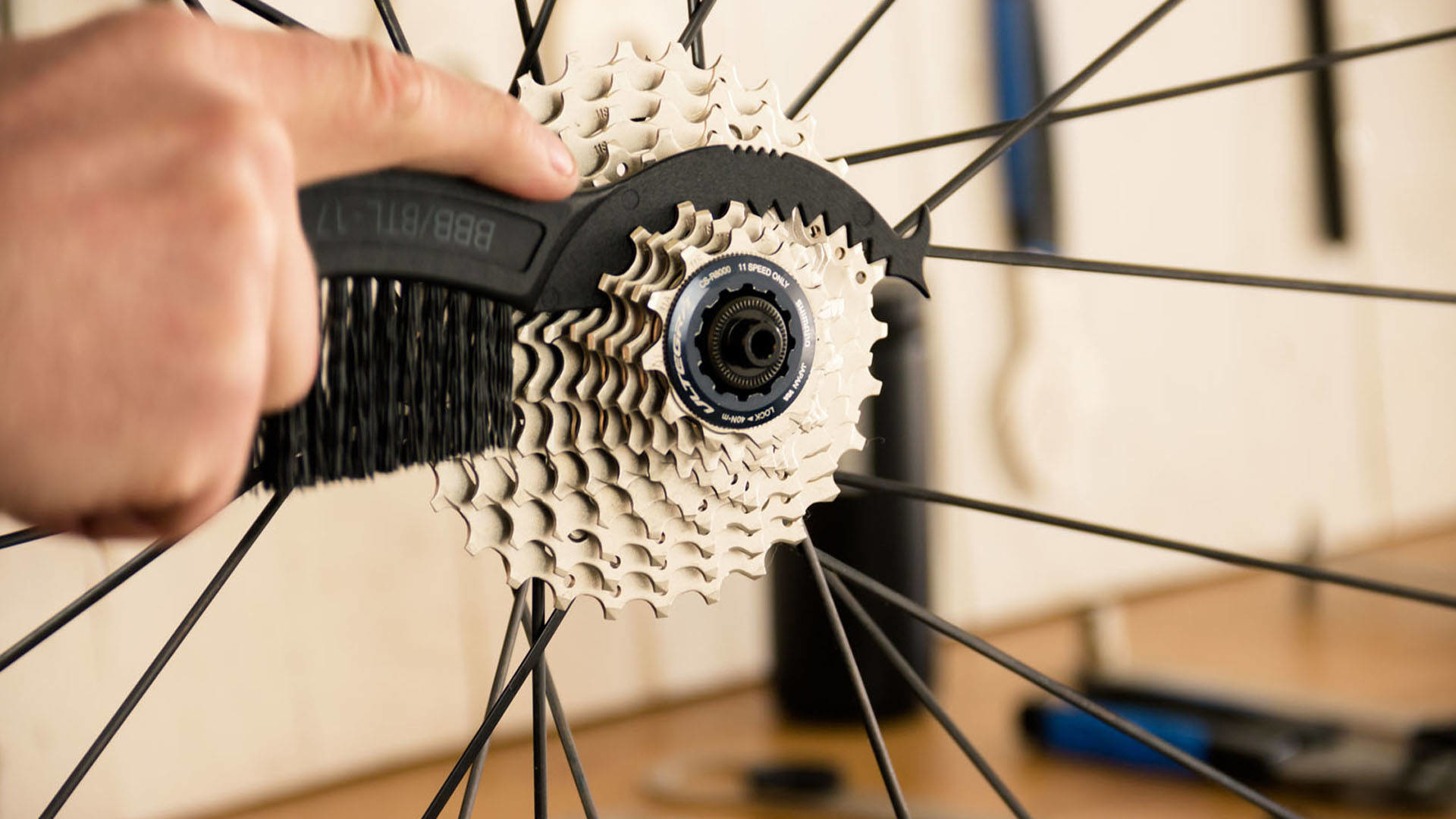 Osoba czyści kasetę roweru szczotką.