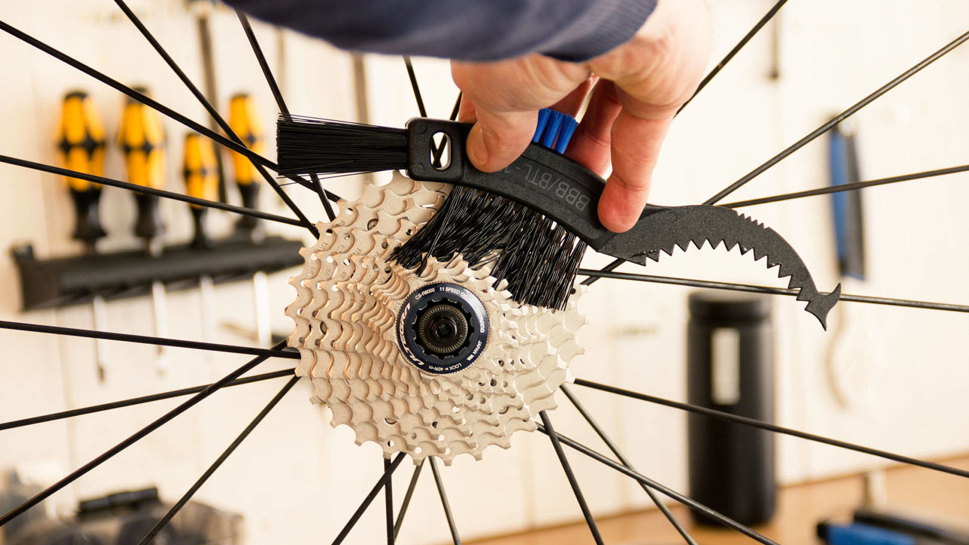 Osoba czyszcząca zębatki roweru szczotką.