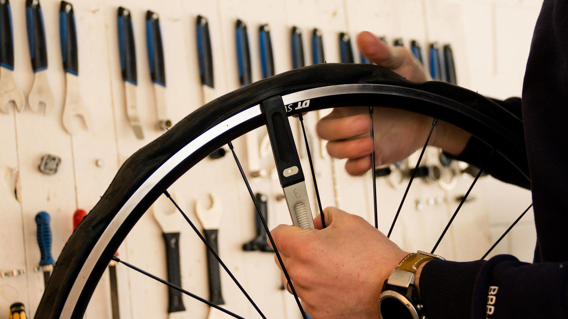 Osoba naprawia oponę rowerową. Narzędzia i inne części znajdują się na białym tle.