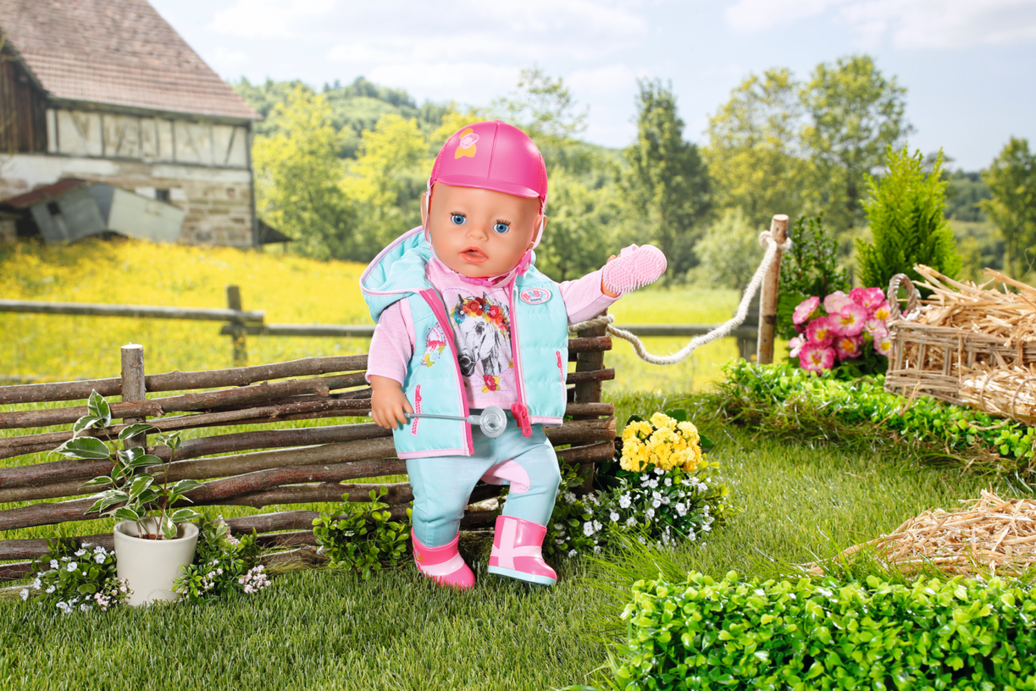 Lalka w stroju jeździeckim stoi na trawiastym terenie z płotem i żółtymi kwiatami w tle.