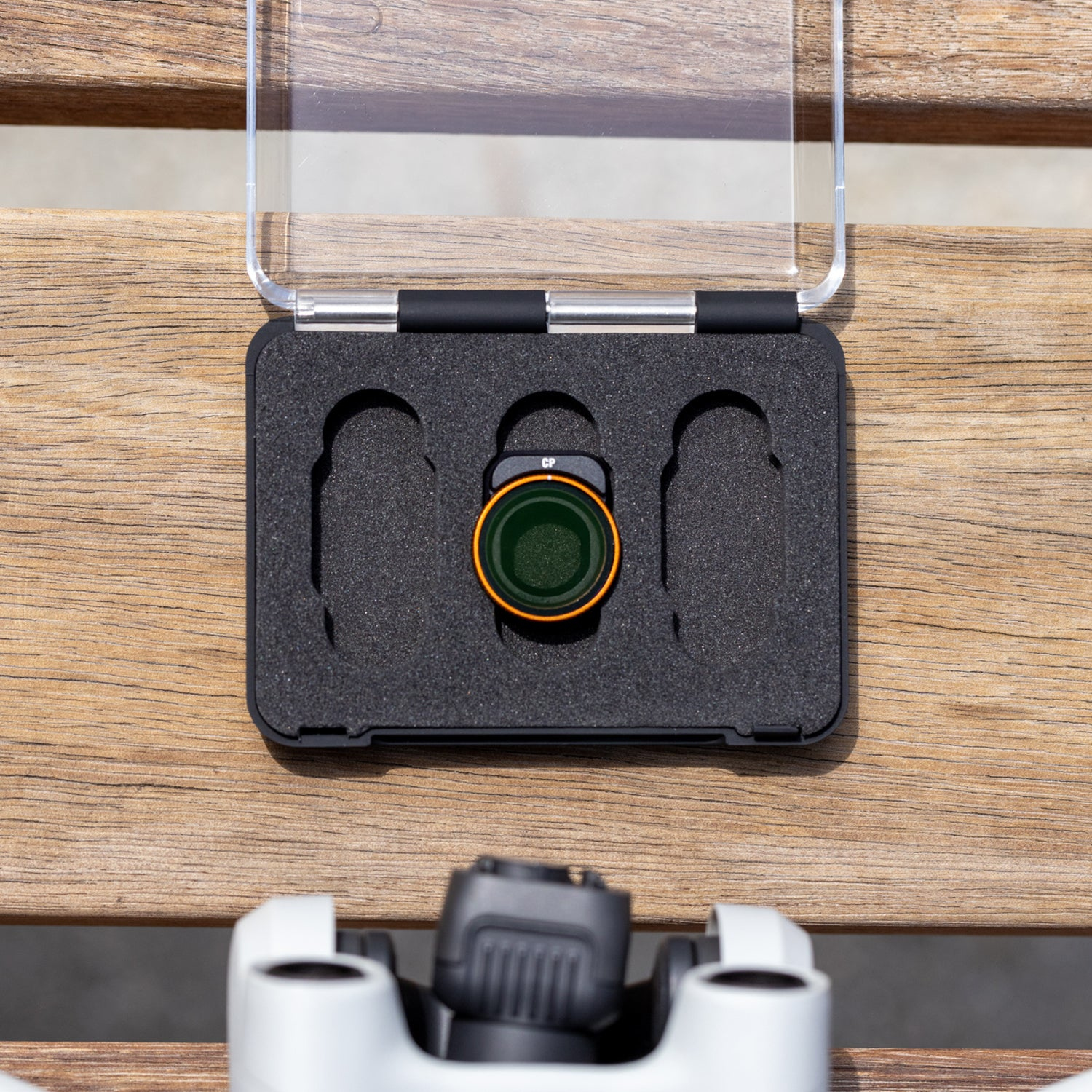 Zbliżenie filtrów obiektywu aparatu. Jeden filtr jest włożony do aparatu. Drewniana powierzchnia.