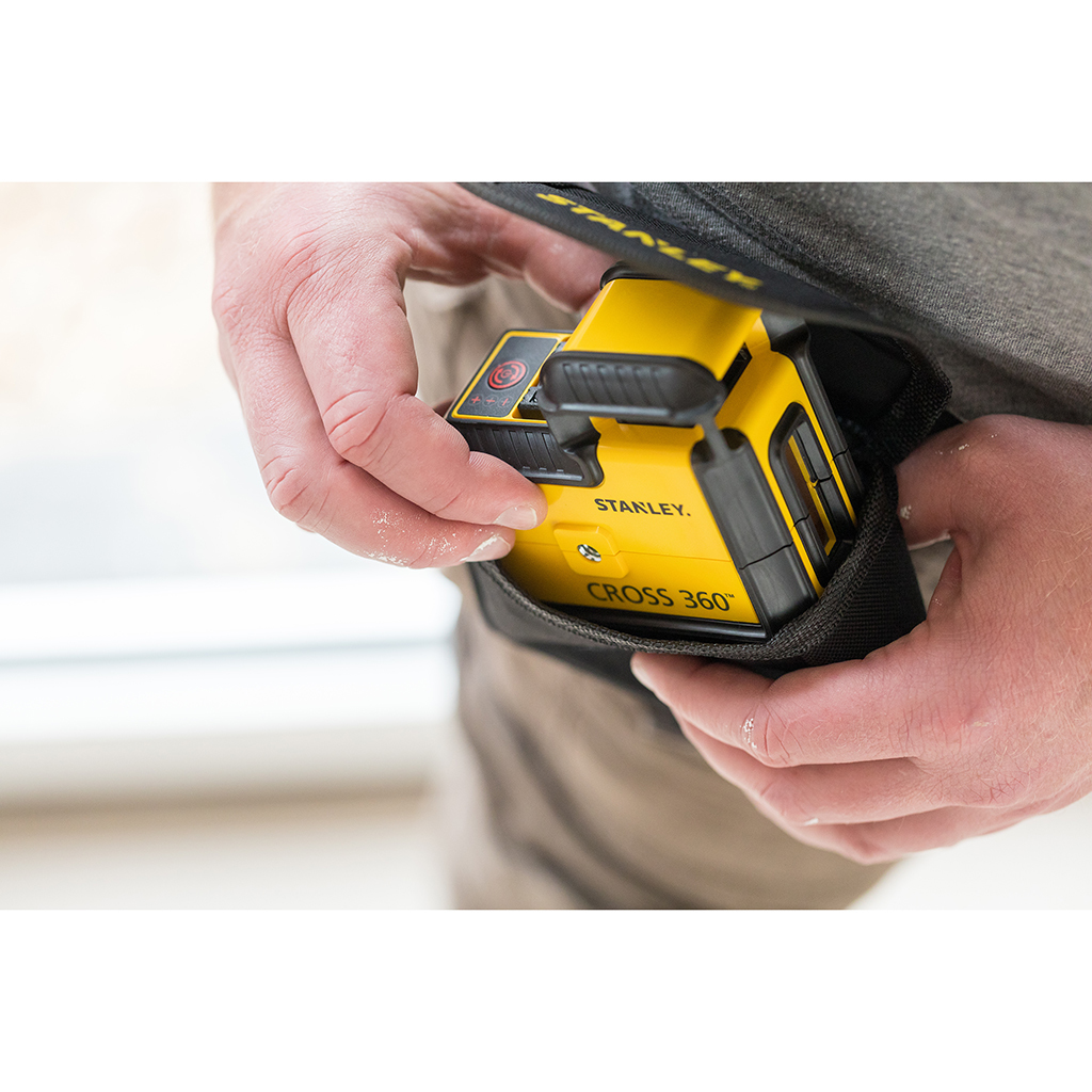Osoba trzyma żółto-czarny laser Stanley Cross 360 w czarnym etui.