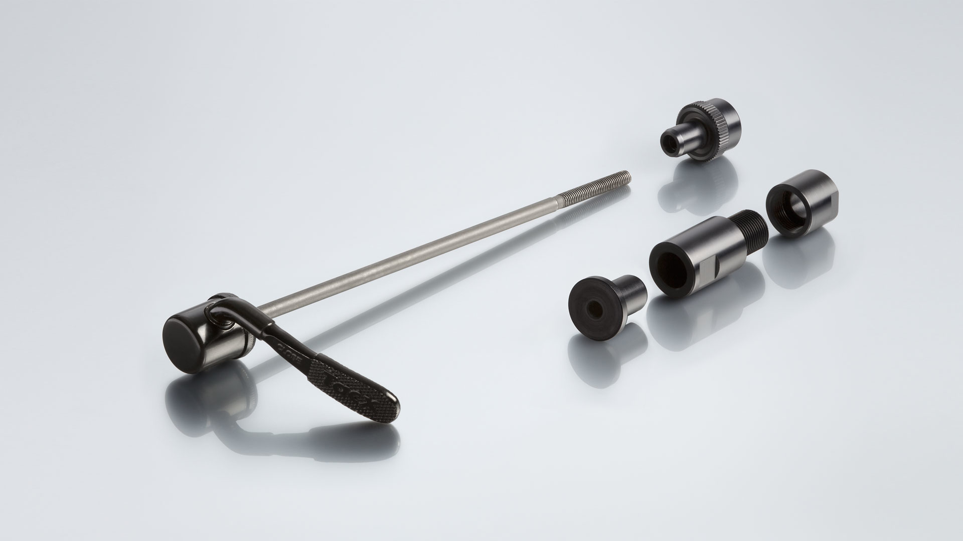 Różne części rowerowe: szybkozamykacz, małe śruby i inne elementy metalowe.