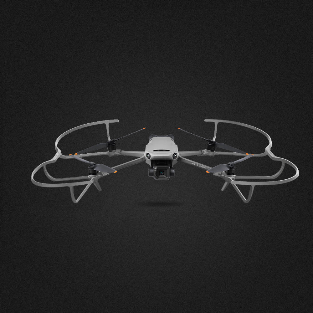 Dron z góry z ramą ochronną. Szary korpus, śmigło i kamera na czarnym tle.