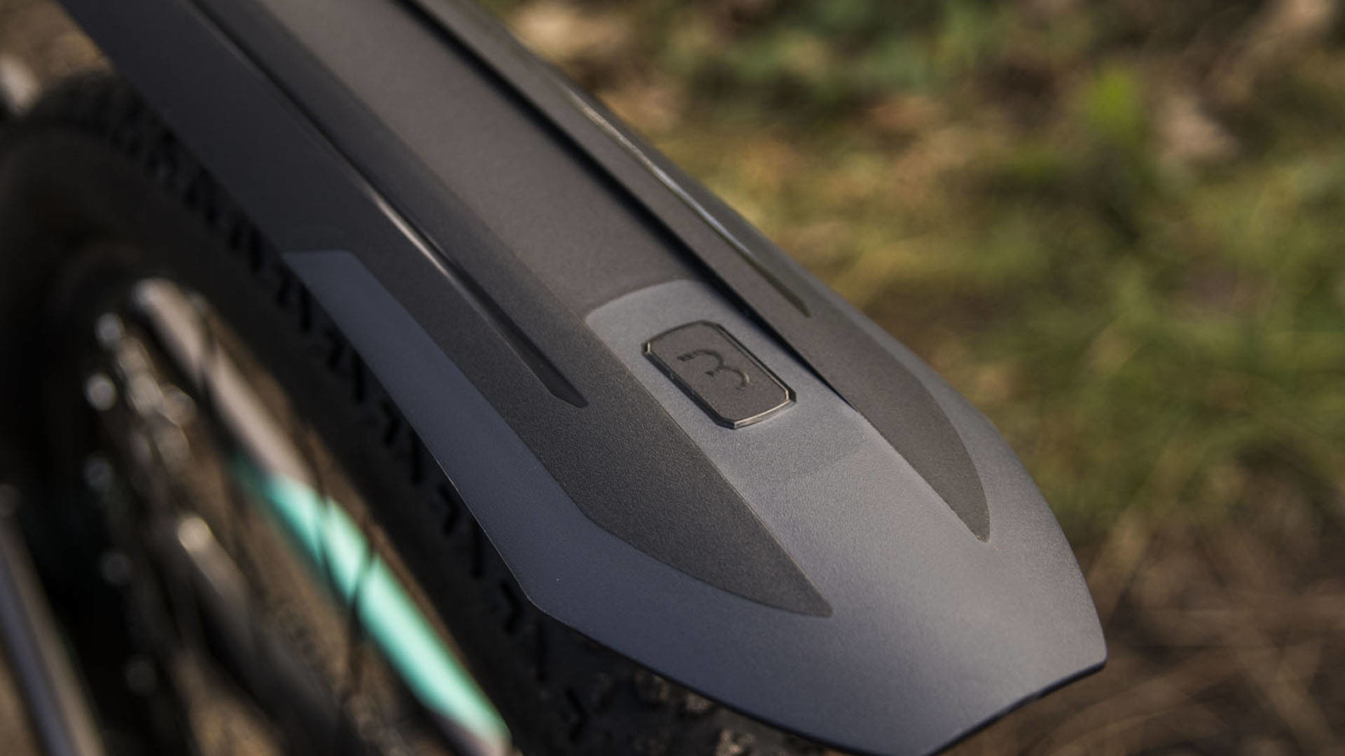 Zbliżenie czarnego błotnika rowerowego, szczegół marki, na rozmytym tle.