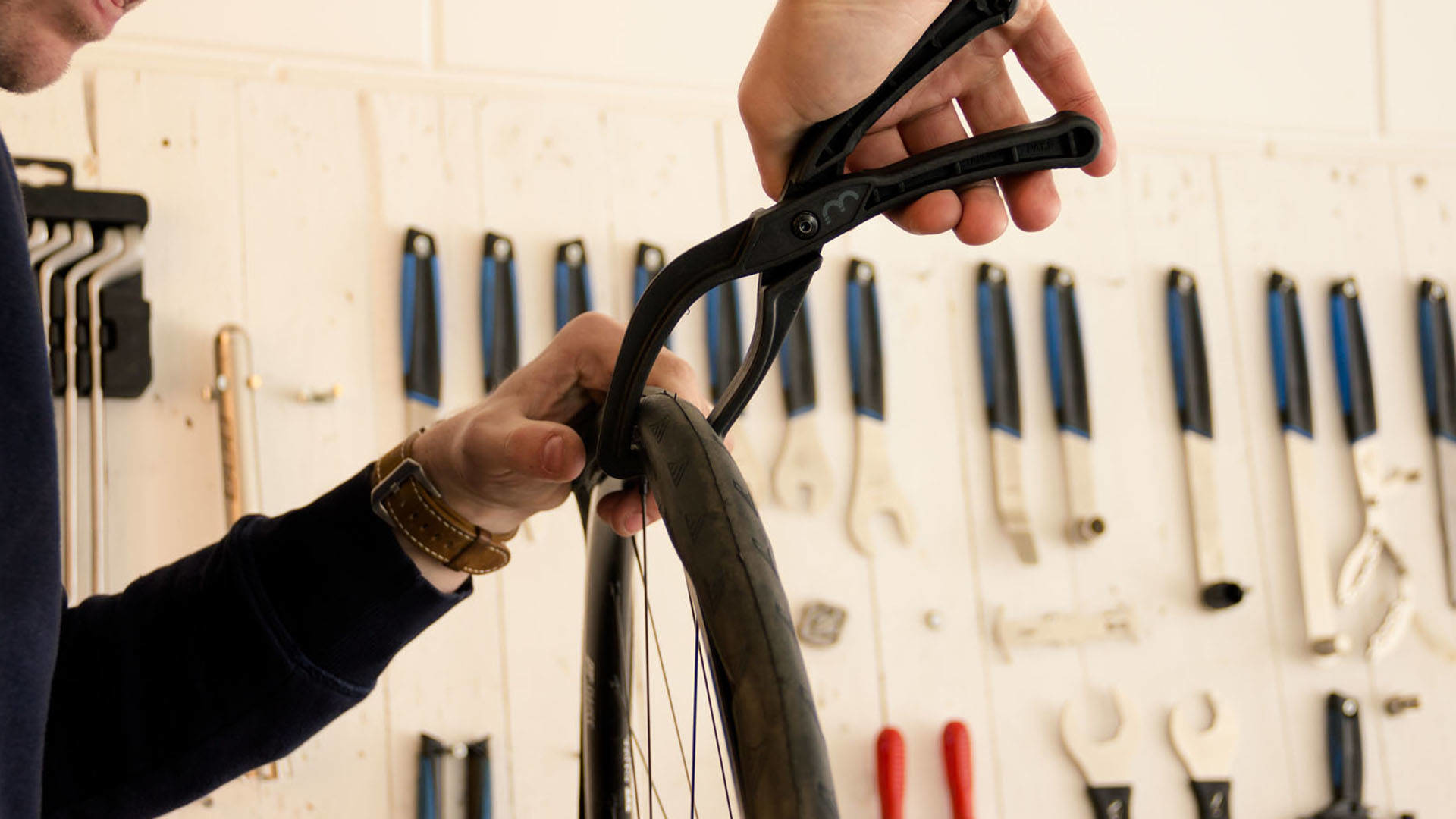 Osoba używa czarnej łyżki do opon do zdjęcia opony z koła roweru.