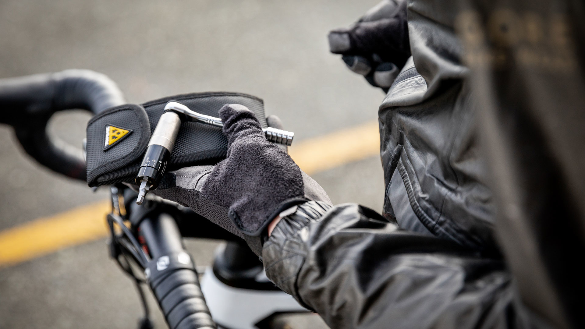 Osoba używa zestawu narzędzi rowerowych, trzymając klucz. Ujęcie zbliżeniowe.