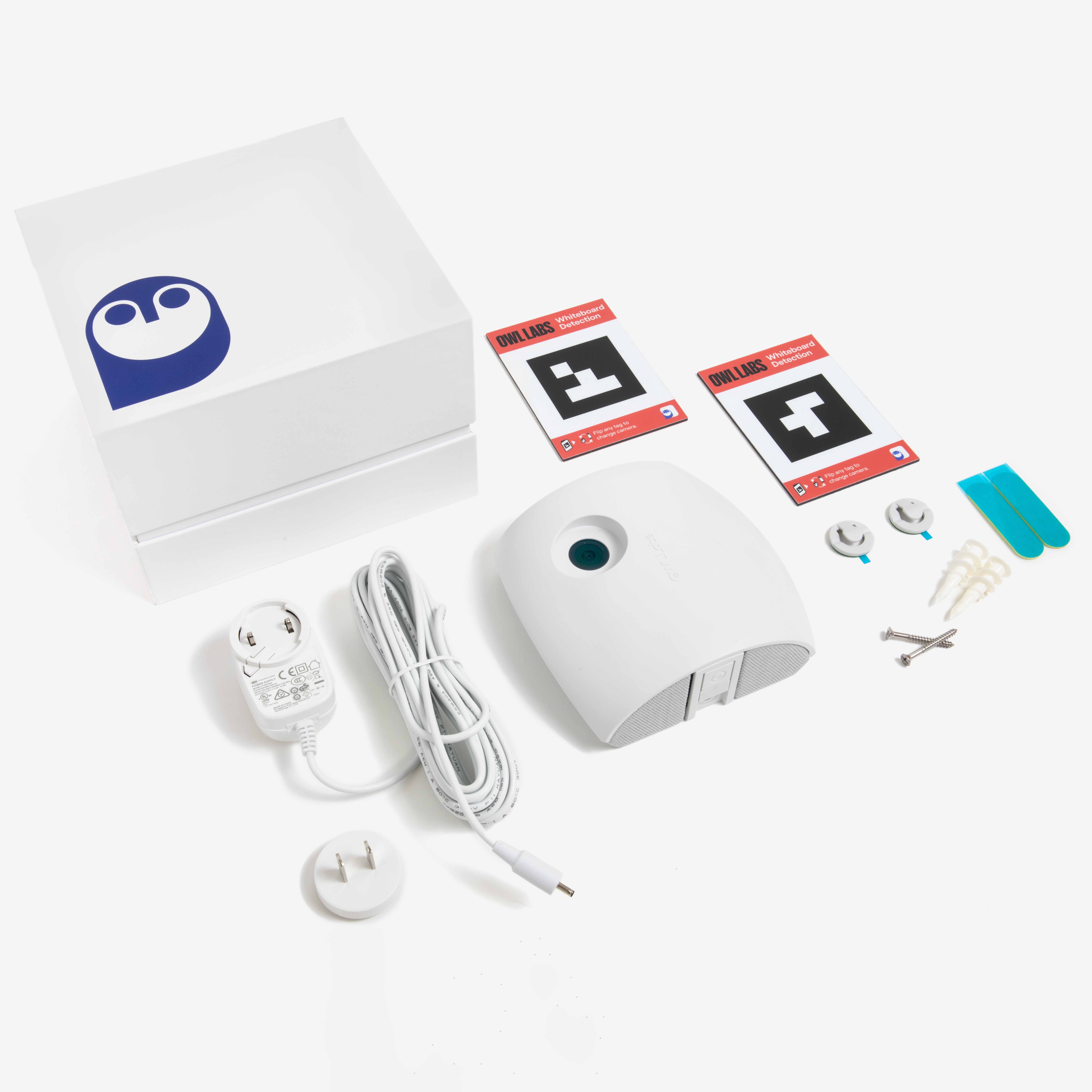 Ein weißes Owl Labs-Gerät und Zubehör, einschließlich eines Netzadapters und eines Ladekabels.