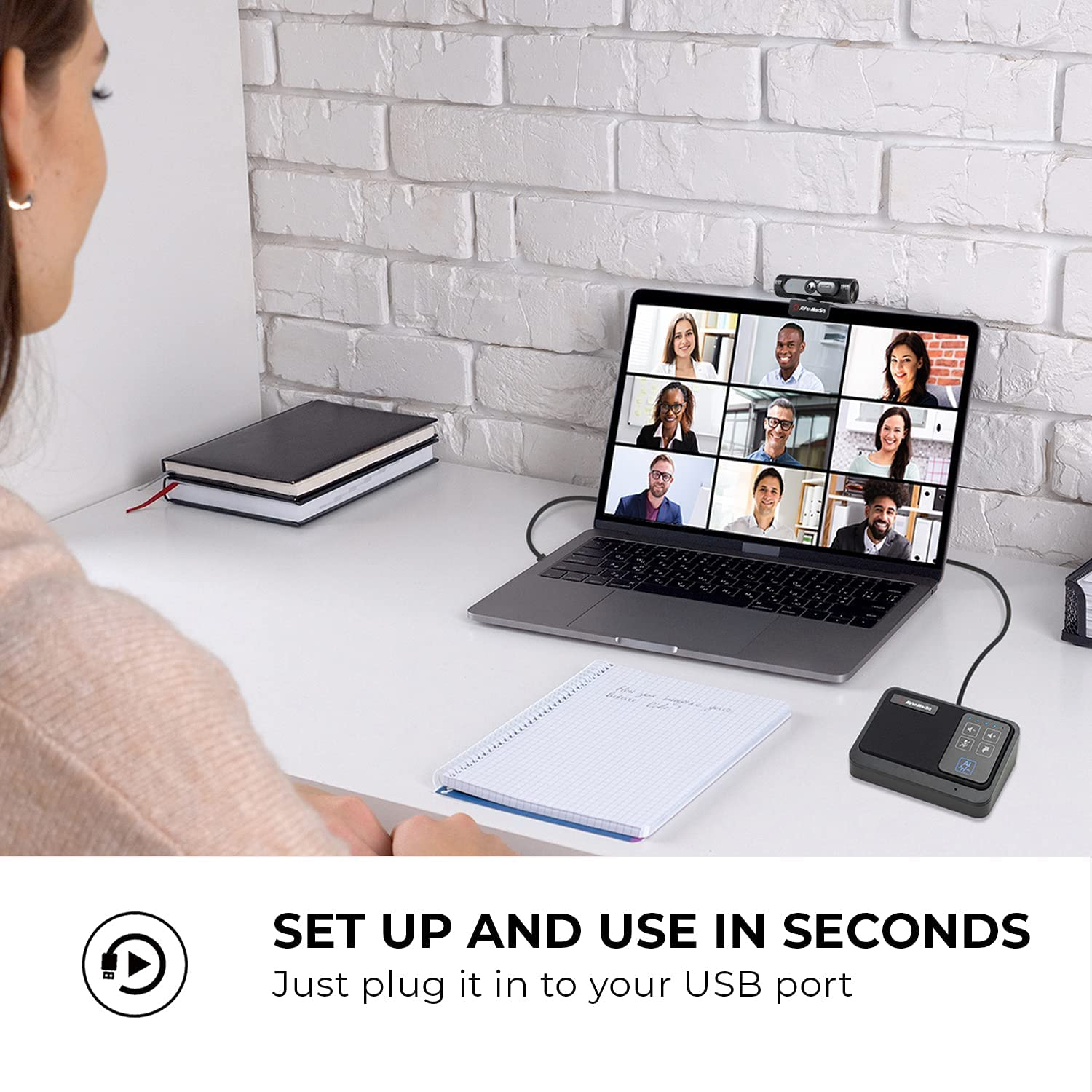 Una donna in videochiamata con un laptop, una webcam e un dispositivo.