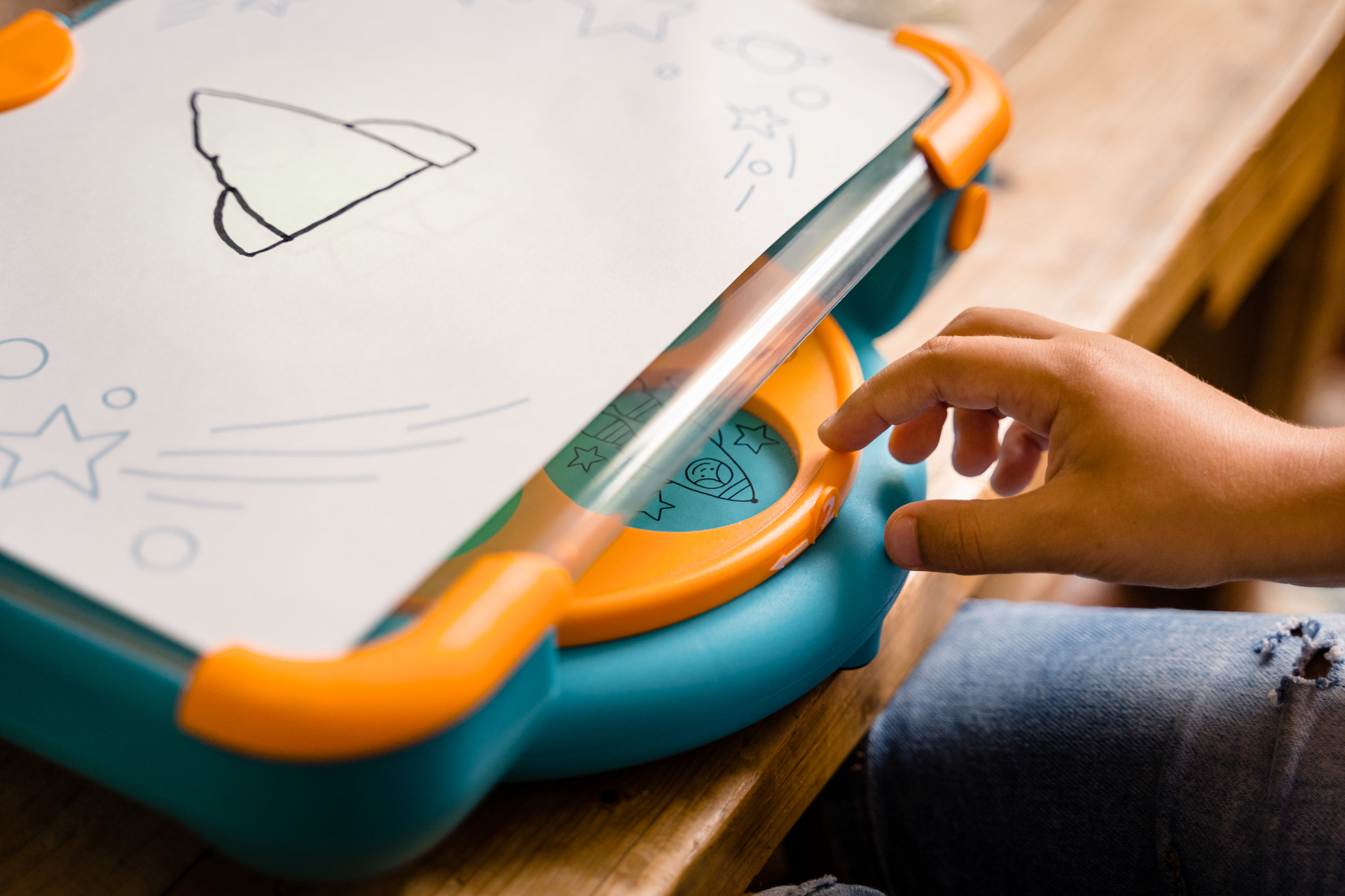 Ręka dziecka używająca zabawki do rysowania. Zabawka jest niebiesko-pomarańczowa.